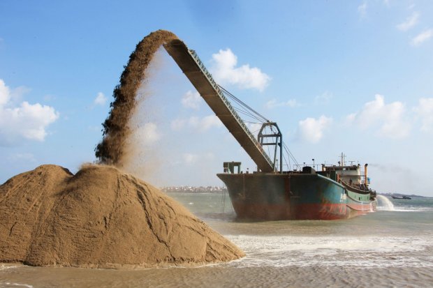 a boat panning sea sand for reclamation