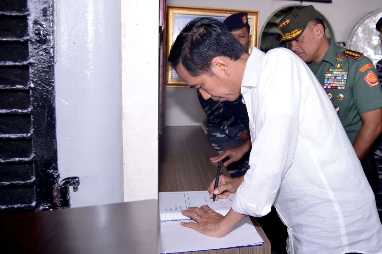 Presiden Joko Widodo membubuhkan tanda tangan ditemani Panglima TNI Jenderal TNI Gatot Nurmantyo, saat meninjau KRI Imam Bonjol 383, yang berlayar di perairan Natuna, Kepulauan Riau, Kamis (23/6).