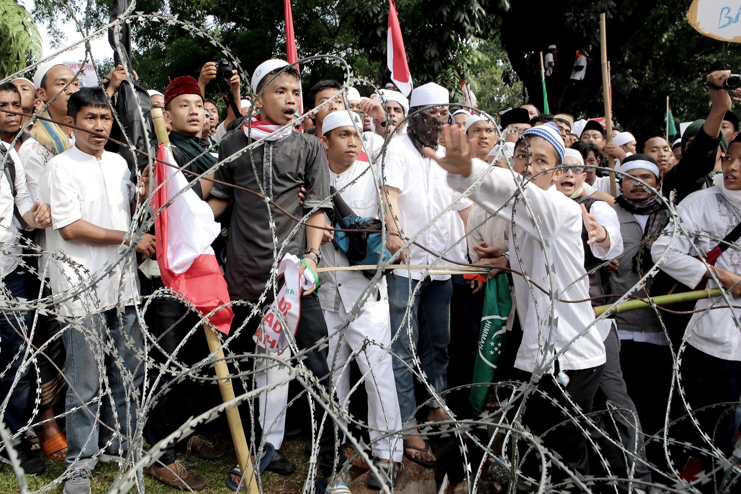 Massa mencoba menerobos kawat berduri yang dipasang oleh petugas untuk mencegah pengunjuk rasa mendekati Istana Merdeka saat unjuk rasa di Jakarta, Jumat (4/11).