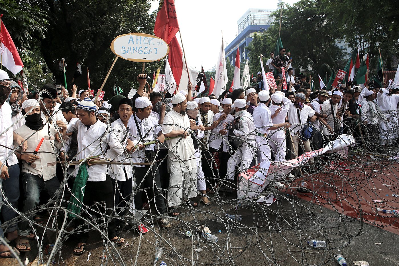 Massa mencoba menerobos kawat berduri yang dipasang oleh petugas untuk mencegah pengunjuk rasa mendekati Istana Merdeka saat unjuk rasa di Jakarta, Jumat (4/11).
