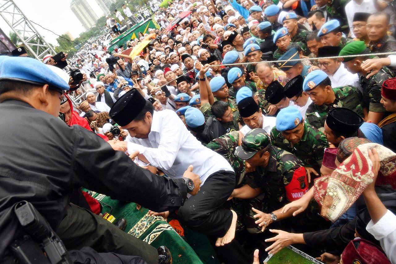 Presiden Joko Widodo berusaha menaiki panggung yang ada di lokasi kasi untuk bergabung melakukan shalat jumat bersama di Silang Monas, Jakarta.