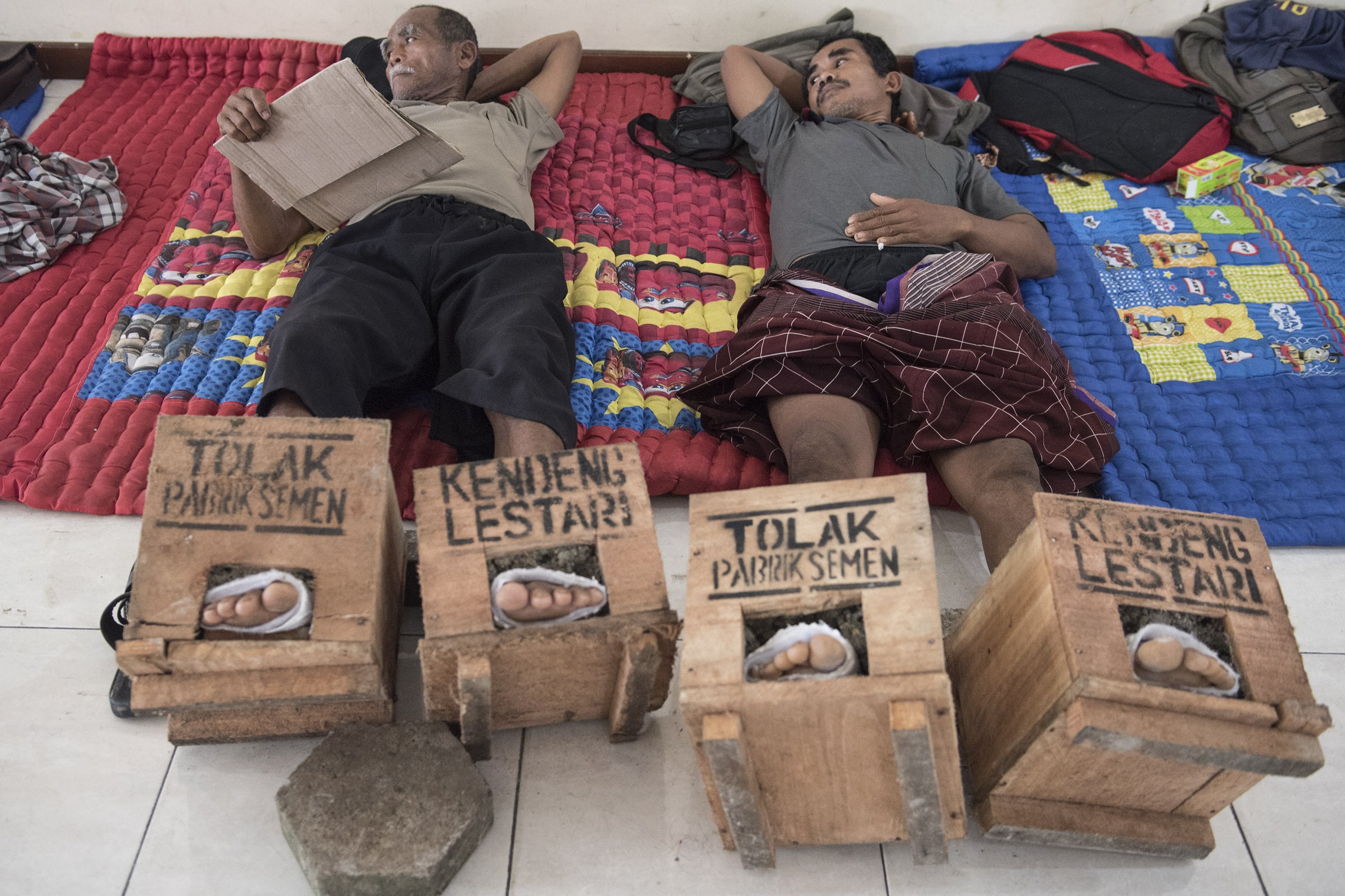 Dua petani dari Pegunungan Kendeng beristirahat dengan kaki terpasung semen di LBH, Jakarta, Sabtu (18/3). Jumlah petani yang memasung kaki dengan semen untuk menolak pembangunan pabrik semen di Pegunungan Kendeng, Jawa Tengah, terus bertambah hingga 50 orang. 