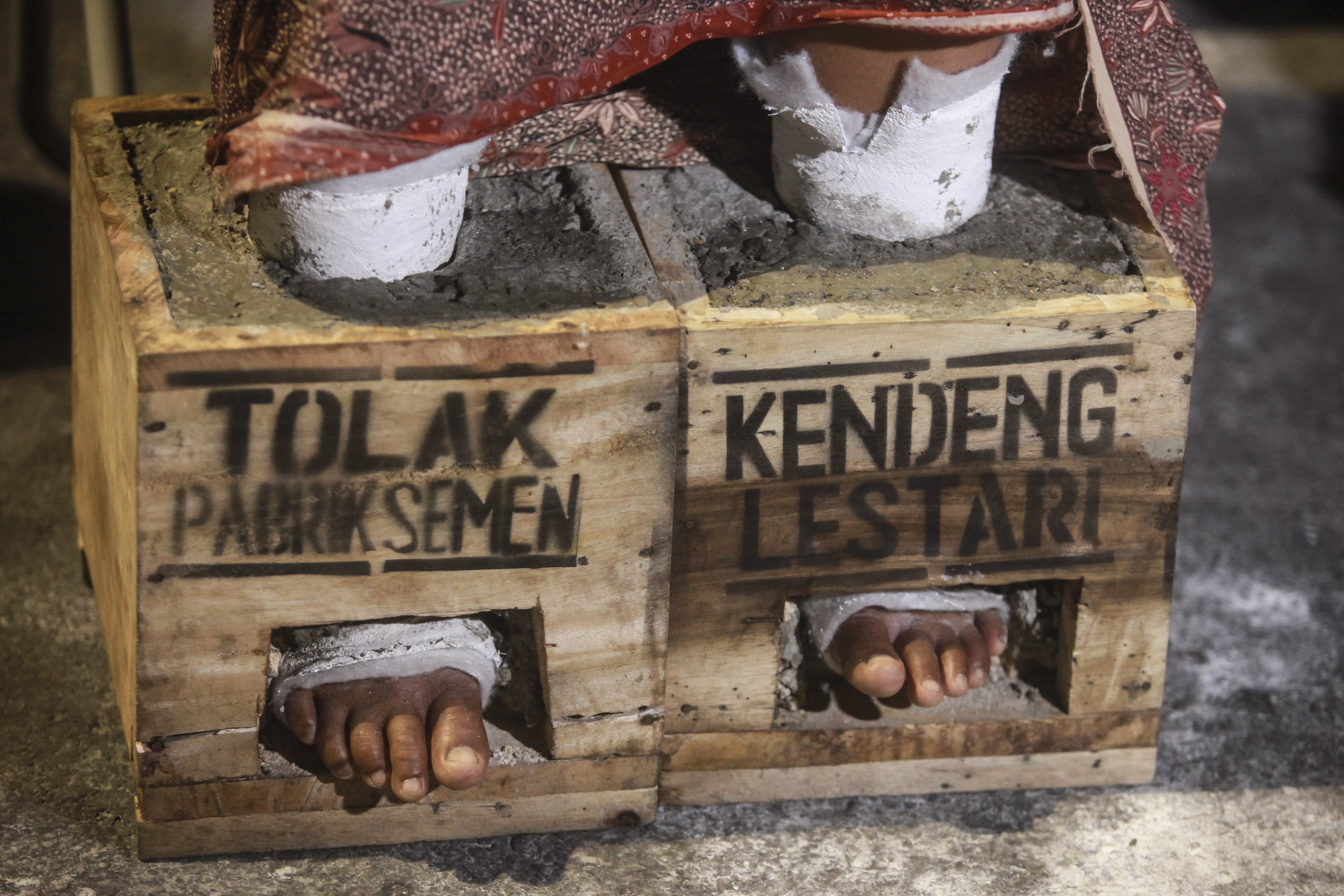 Petani Pegunungan Kendeng memasung kakinya dengan semen saat menggelar aksi di depan Istana Merdeka, Jakarta, Senin (13/3). Mereka meminta kepada Presiden Joko Widodo untuk menghentikan izin lingkungan pembangunan dan pertambangan pabrik PT Semen Indonesia Tbk.