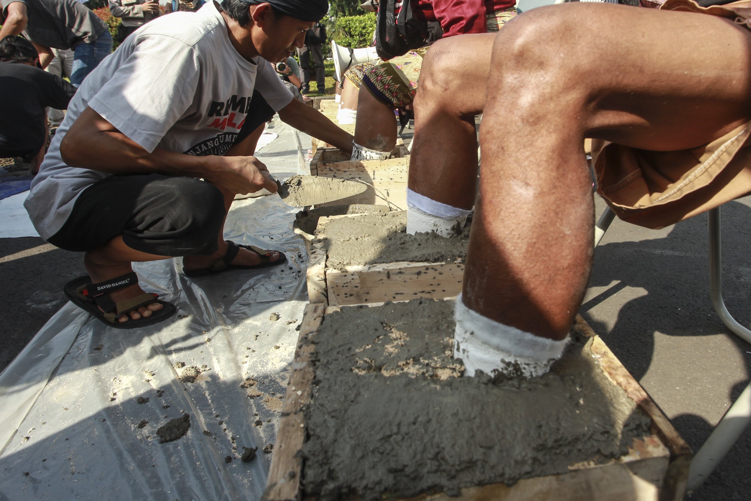 Para petani Pegunungan Kendeng memasung kakinya dengan semen saat menggelar aksi di depan Istana Merdeka, Jakarta, Senin (13/3). Mereka meminta kepada Presiden Joko Widodo untuk menghentikan izin lingkungan pembangunan dan pertambangan pabrik PT Semen Indonesia Tbk.
