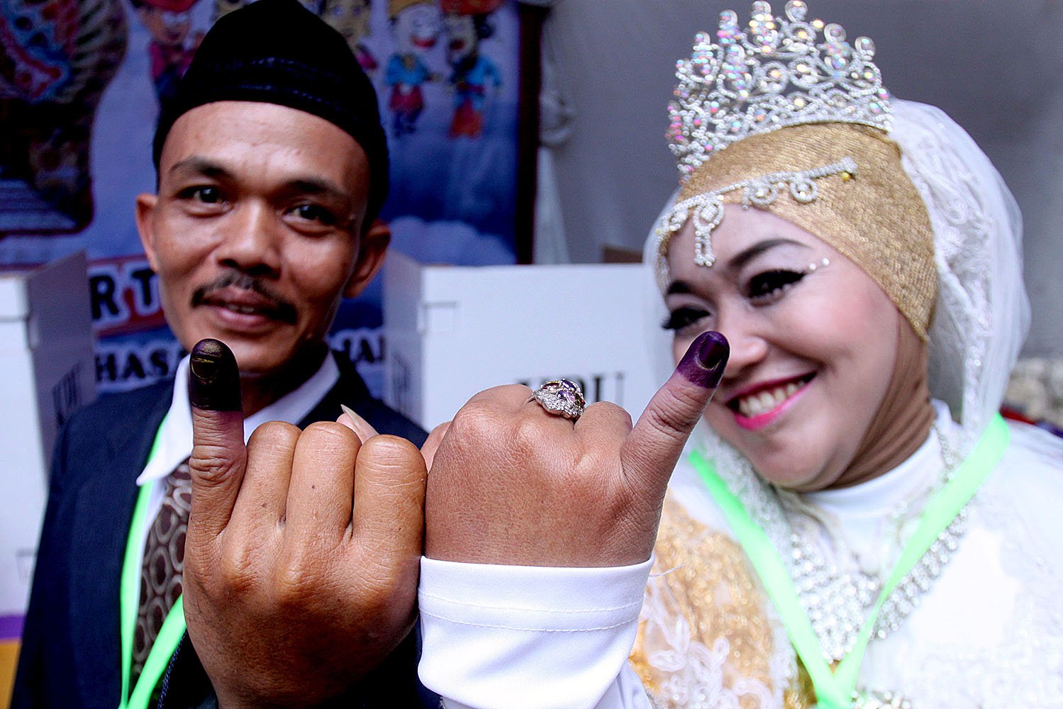 Petugas KPPS yang menggunakan kostum pernikahan menunjukkan jari setelah mencoblos di TPS 02, Cijantung, Jakarta Timur, Rabu (19/4).