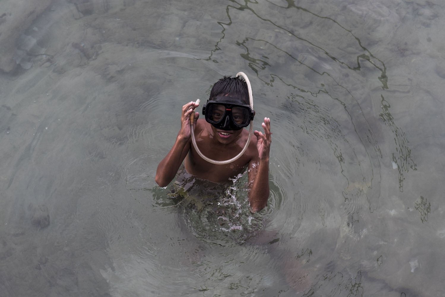 Seorang bocah menggunakan selang air saat berenang di perairan pulau Sedanau di Kabupaten Natuna, Kepulauan Riau, Rabu (2/8).