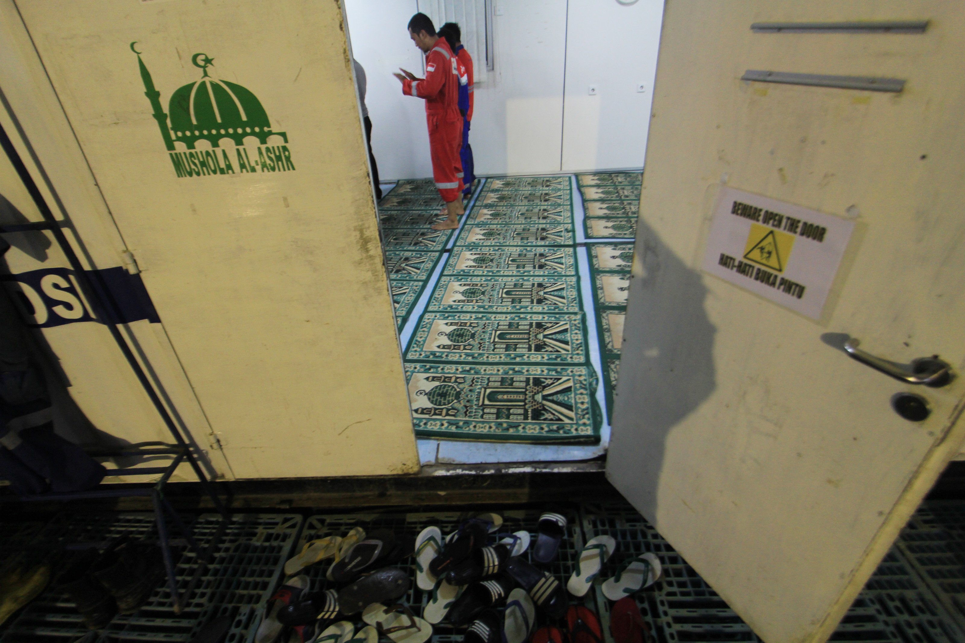 Sejumlah pekerja menunaikan Salat Magrib di dalam kontainer di Rig Jatiasri-9, Subang, Jawa Barat, Kamis (1/2). 