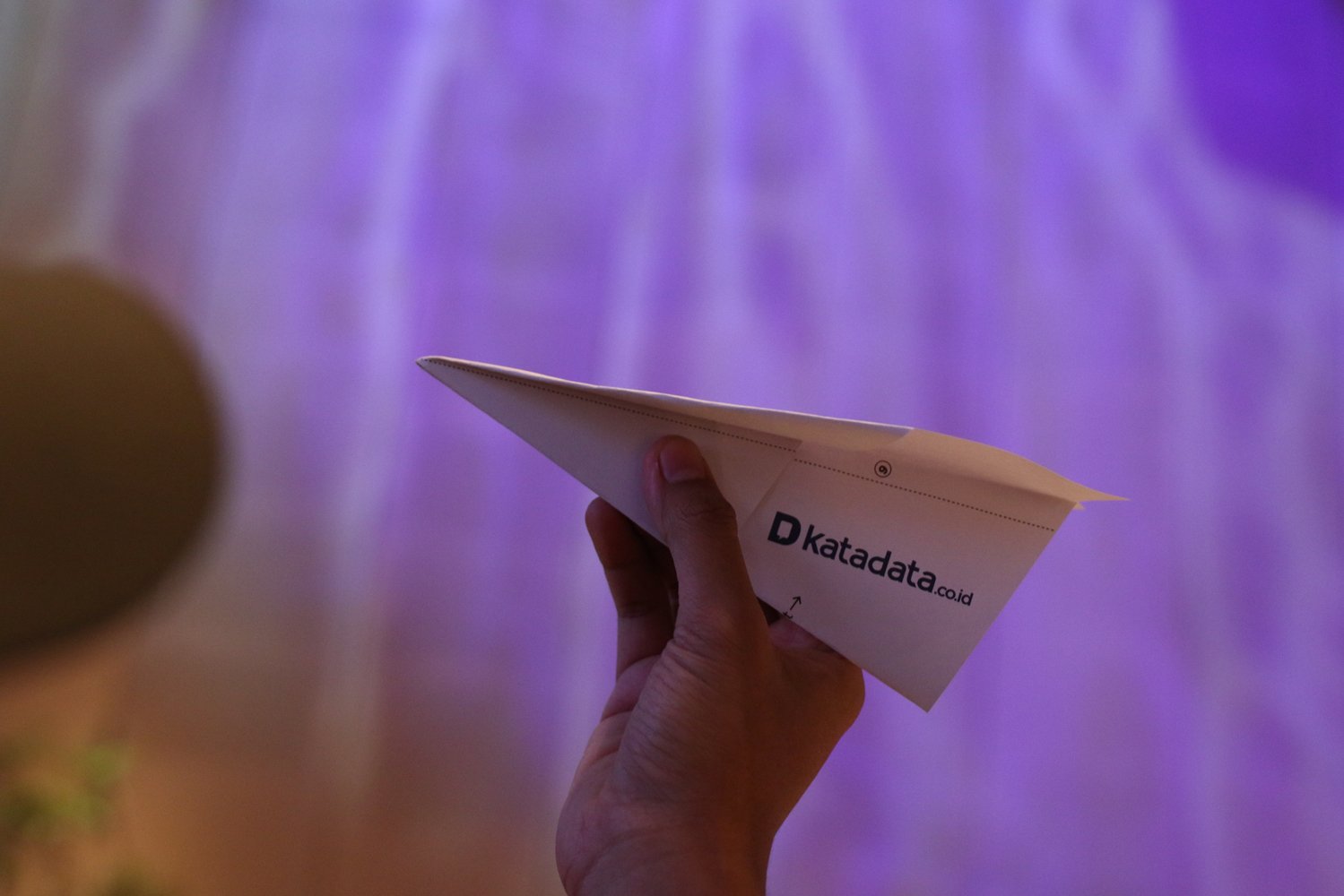 Pesawat kertas Katadata yang siap diterbangkan dengan logo baru tercetak.