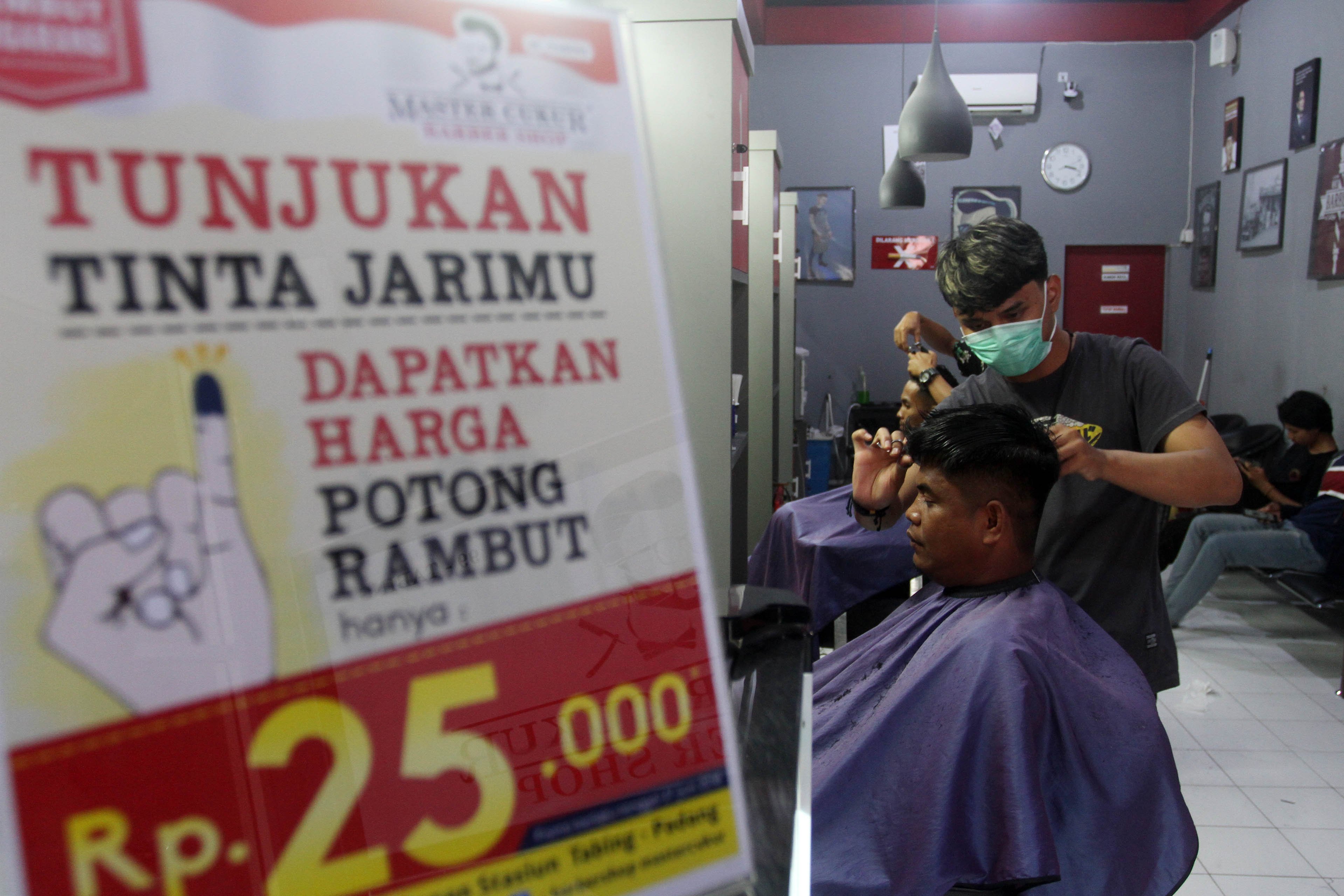 Sejumlah warga memotong rambutnya di Master Baber Shop, Padang, Sumatera Barat, Rabu (27/6). Penggelola tempat pangkas rambut ini memberikan harga spesial Rp 25.000 -harga normal Rp 35.000- pada warga yang menyalurkan hak pilihnya dengan memperlihatkan jari bertinta sebagai bukti mengikuti Pilkada Walikota Padang periode 2019-2024.