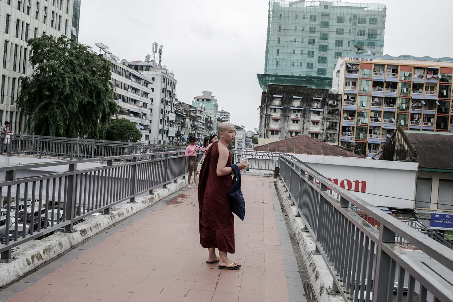 Seorang biksu menikmati pemandangan sore dari atas jembatan penyebrangan di pusat kota yangon, Myanmar.