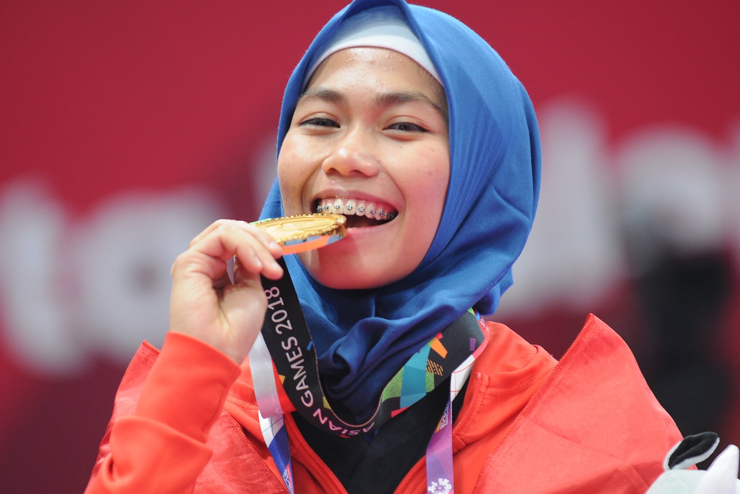 Taekwondoin putri Indonesia, Defia Rosmaniar menggigit medali emas yang diraihnya atas kemenangan di poomsae tunggal putri pertandingan Taekwondo di Asian Games 2018, di Jakarta Convention Center (JCC), Minggu (19/8). 