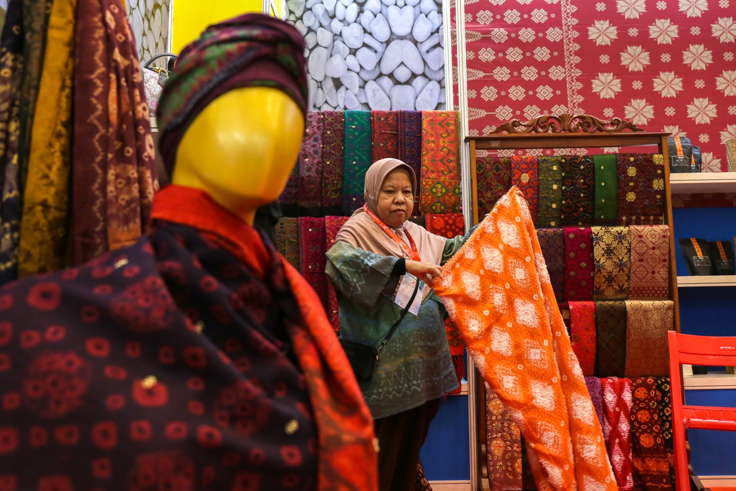 Seorang wanita sedang membentang kain batik dalam acara Trade Expo Indonesia 2018. TEI merupakan ajang promosi tahunan berskala internasional yang menampilkan produk dan jasa Indonesia berorientasi pasar ekspor. 