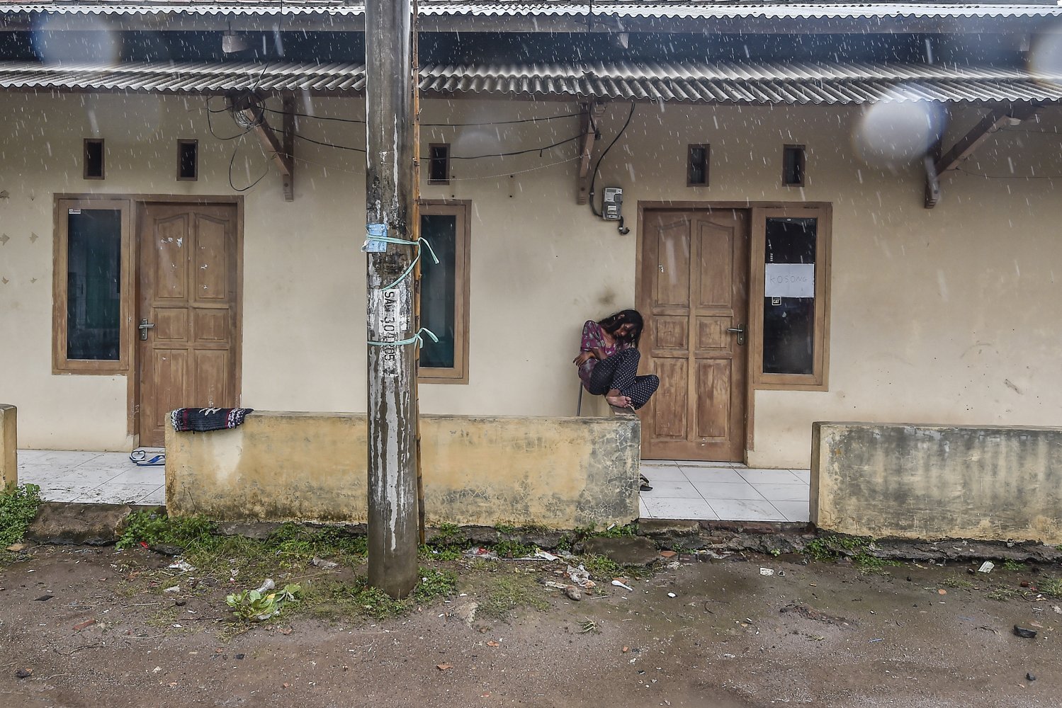 Seorang perempuan tertidur di depan rumah singgah yang tutup pascatsunami di kawasan wisata Pantai Anyer, Banten, Senin (24/12/2018). 