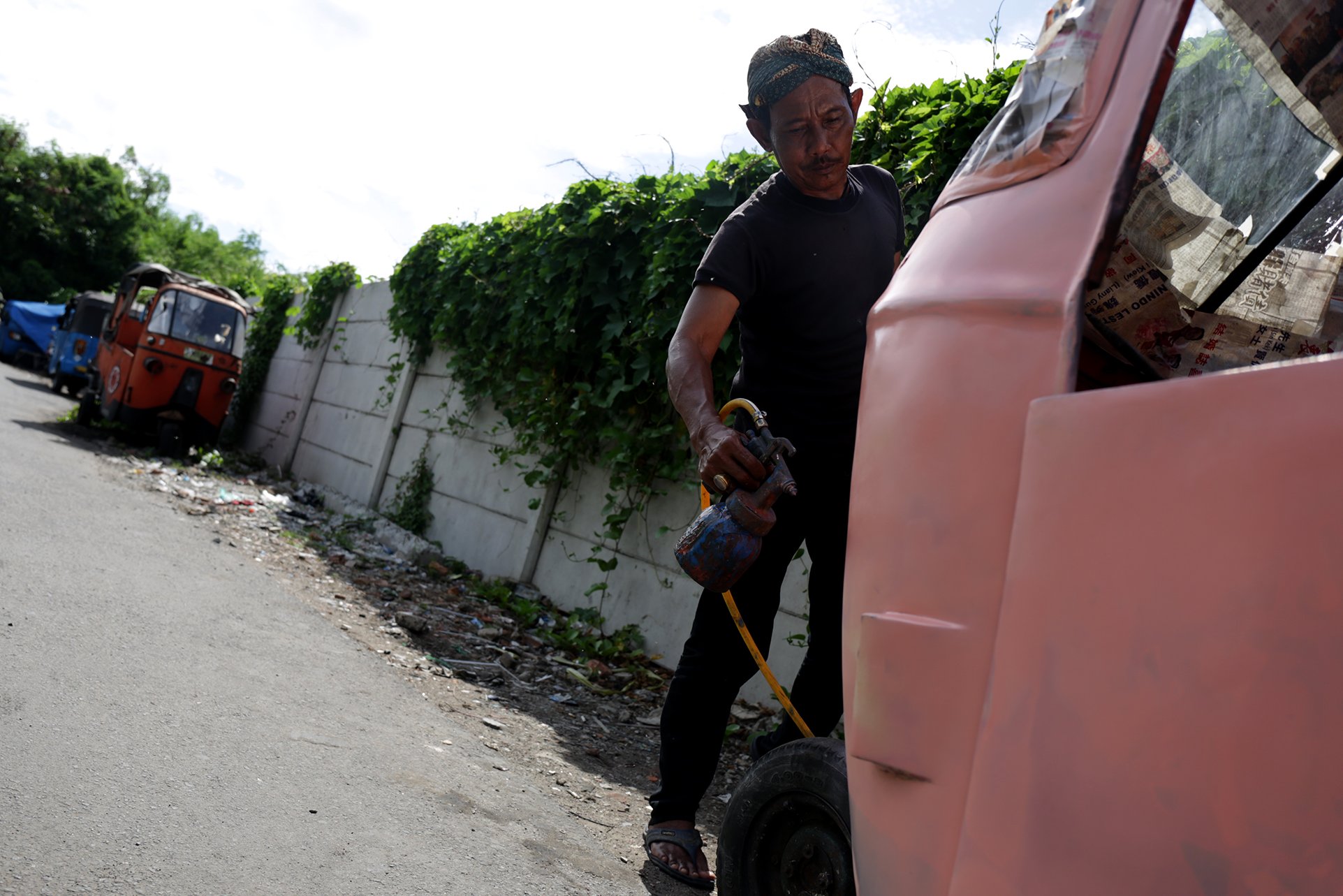  Seorang pria mewarnai bajaj oranye di Cideng, Jakarta Pusat (3/1) untuk dikirim ke Yogyakarta. Bajaj modifikasi juga sudah dikirim ke Lampung.