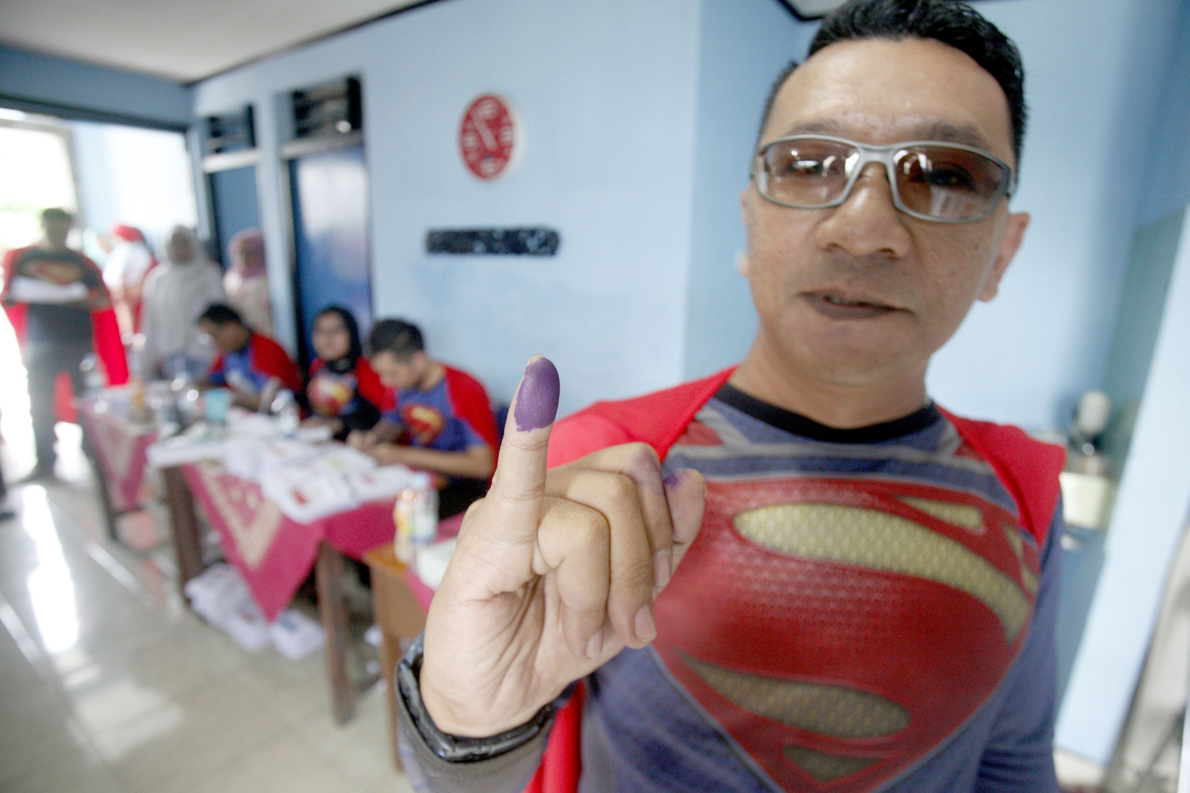 Petugas KPPS menunjukan jari seusai memberikan hak suaranya di TPS 072 Mekarjaya yang bertemakan superman di Depok, Jawa Barat, Rabu (17/4/2019).