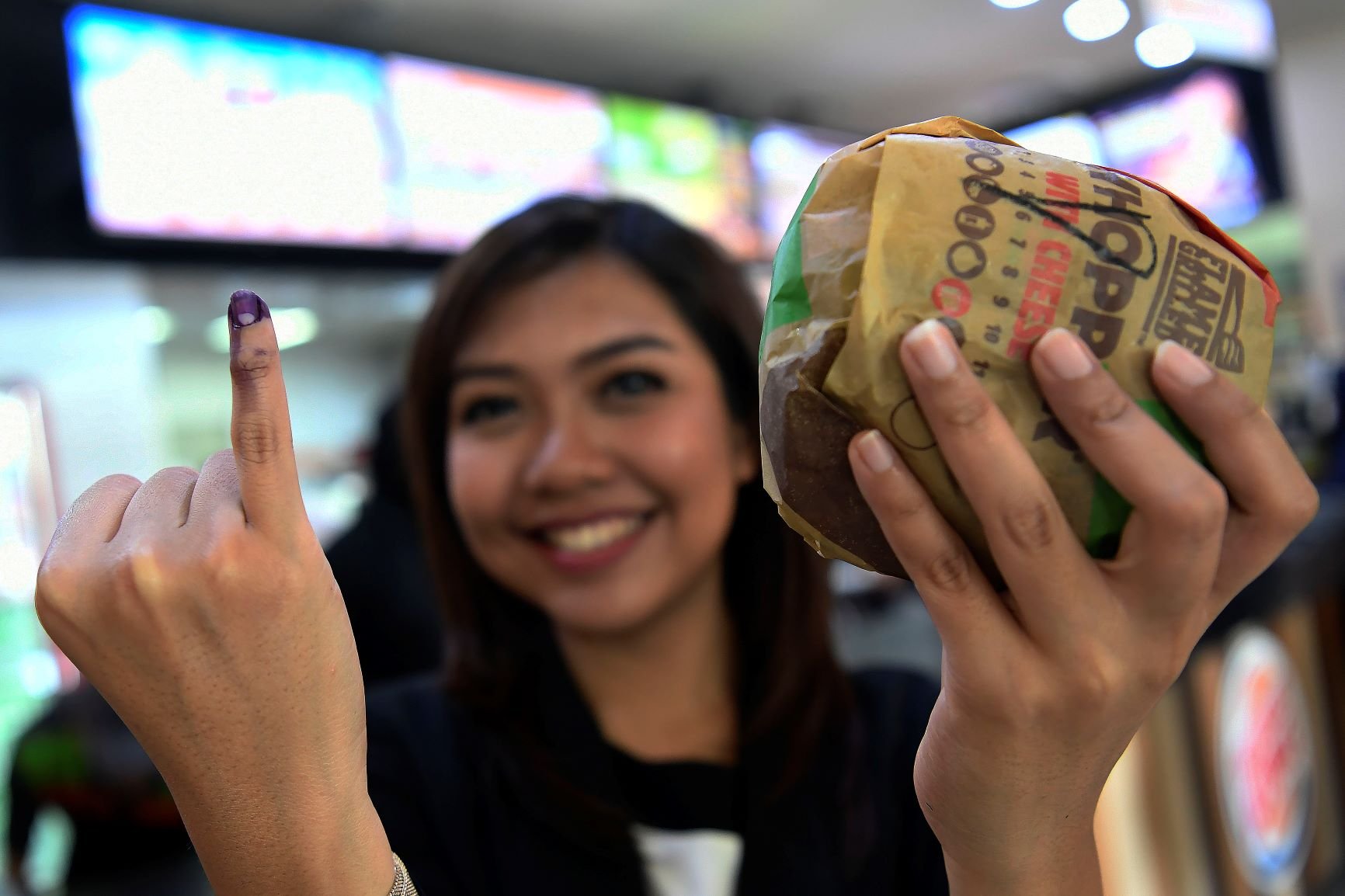 Warga menunjukkan jari yang telah dicelupkan tinta Pemilu saat membeli salah satu makanan siap saji di Jakarta, Rabu (17/4/2019). Sejumlah pusat perbelanjaan dan gerai makanan memberikan potongan harga atau diskon untuk masyarakat yang menggunakan hak pilihnya pada pesta demokrasi Pemilu serentak 2019. 
