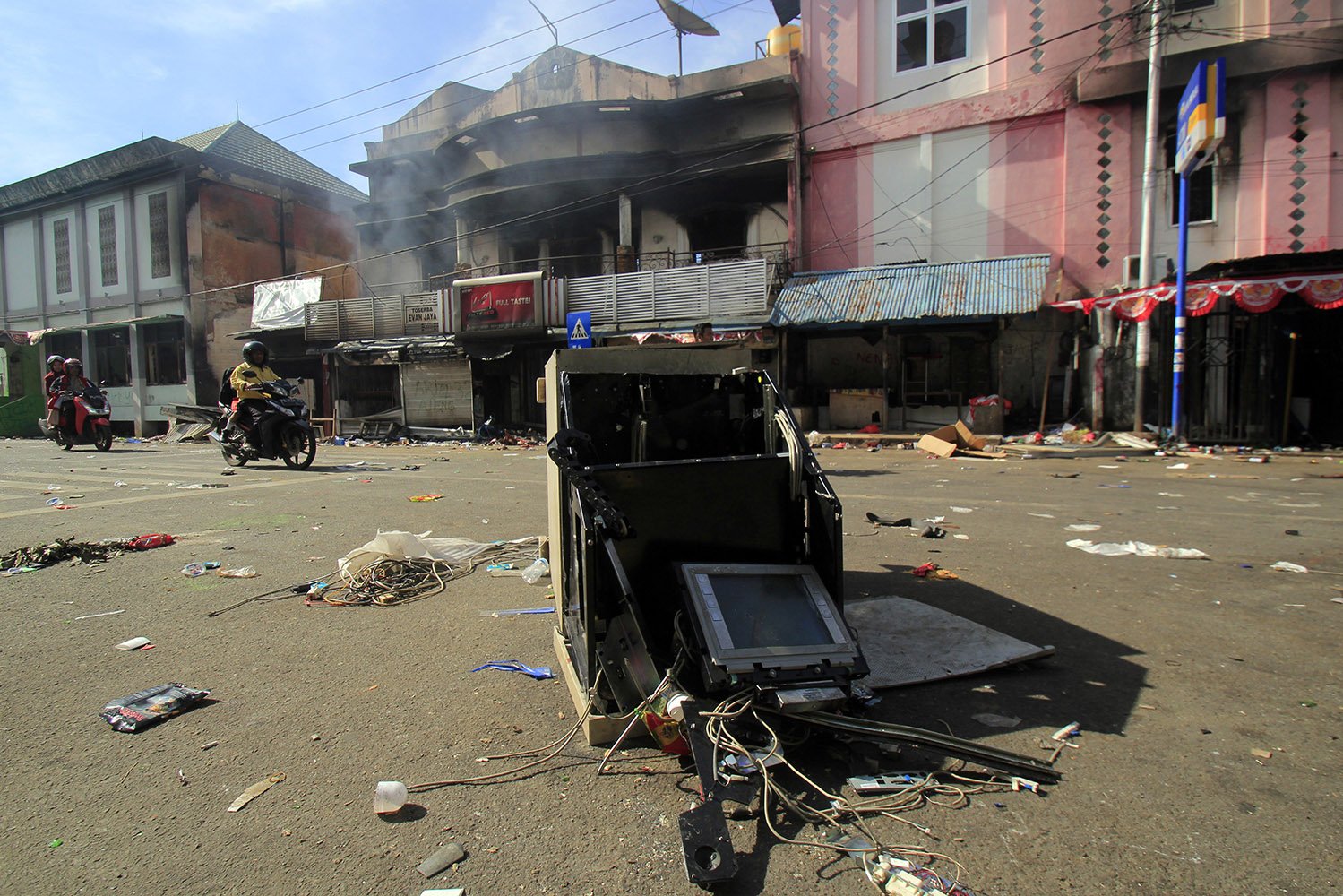Warga melintasi bangunan dan kendaraan yang rusak, di Jayapura, Papua, Jumat (30/8/2019). Sejumlah bangunan dan kendaraan terbakar saat aksi unjuk rasa yang berakhir rusuh, di Jayapura, Kamis (29/8/2019). 