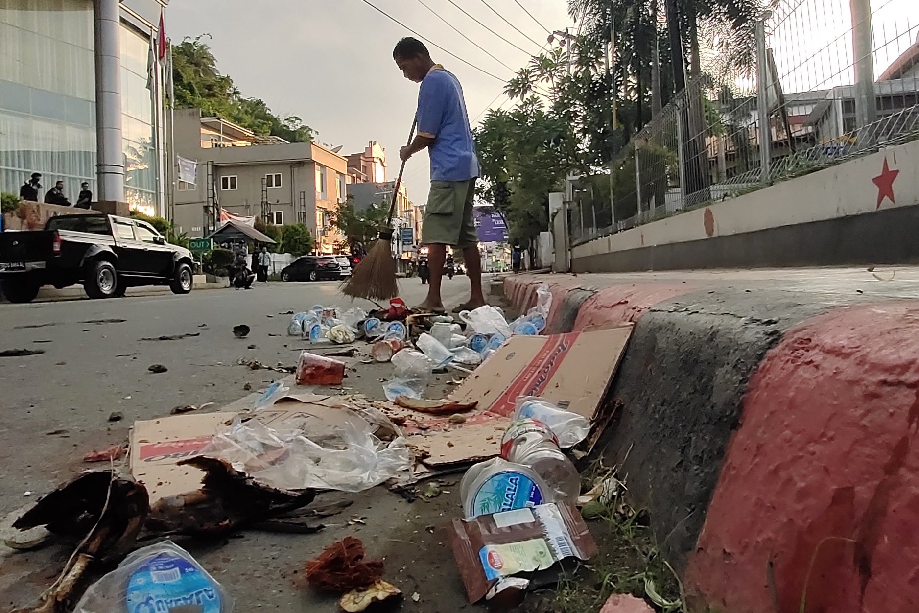 Seorang warga membersihkan sampah seusai berlangsungnya aksi unjuk rasa di Jayapura, Papua, Jumat (30/8/2019). Sejumlah bangunan dan kendaraan terbakar saat aksi pada (29/8/2019).