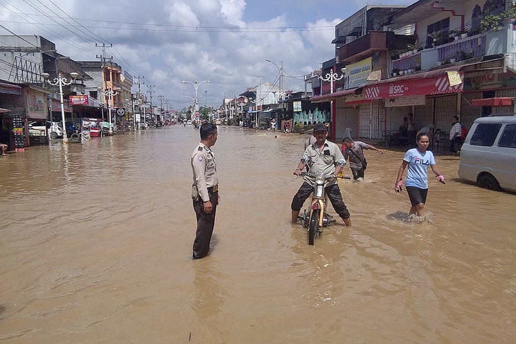Warga melintasi banjir yang menggenangi Kota Pasir Pangaraian, Rokan Hulu, Riau, Selasa (26/11/2019). Banjir yang semakin meluas di Rohan Hulu itu memutus akses jalan utama di wilayah tersebut.