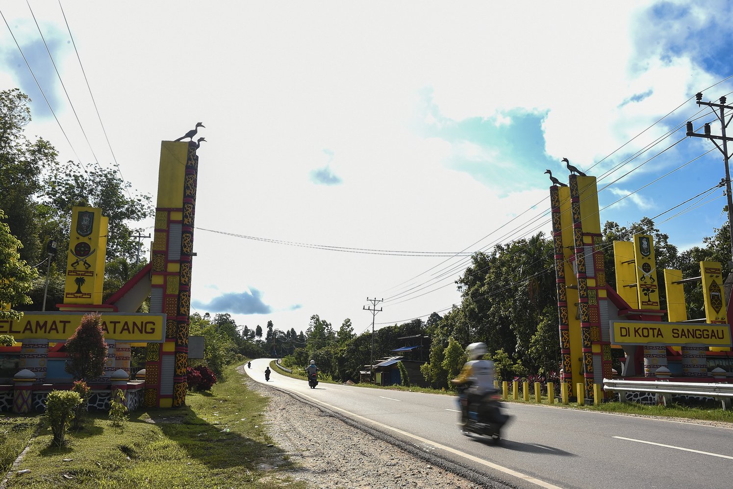 Pengendara melintasi tugu perbatasan Kabupaten Sanggau di Kalimantan Barat.
