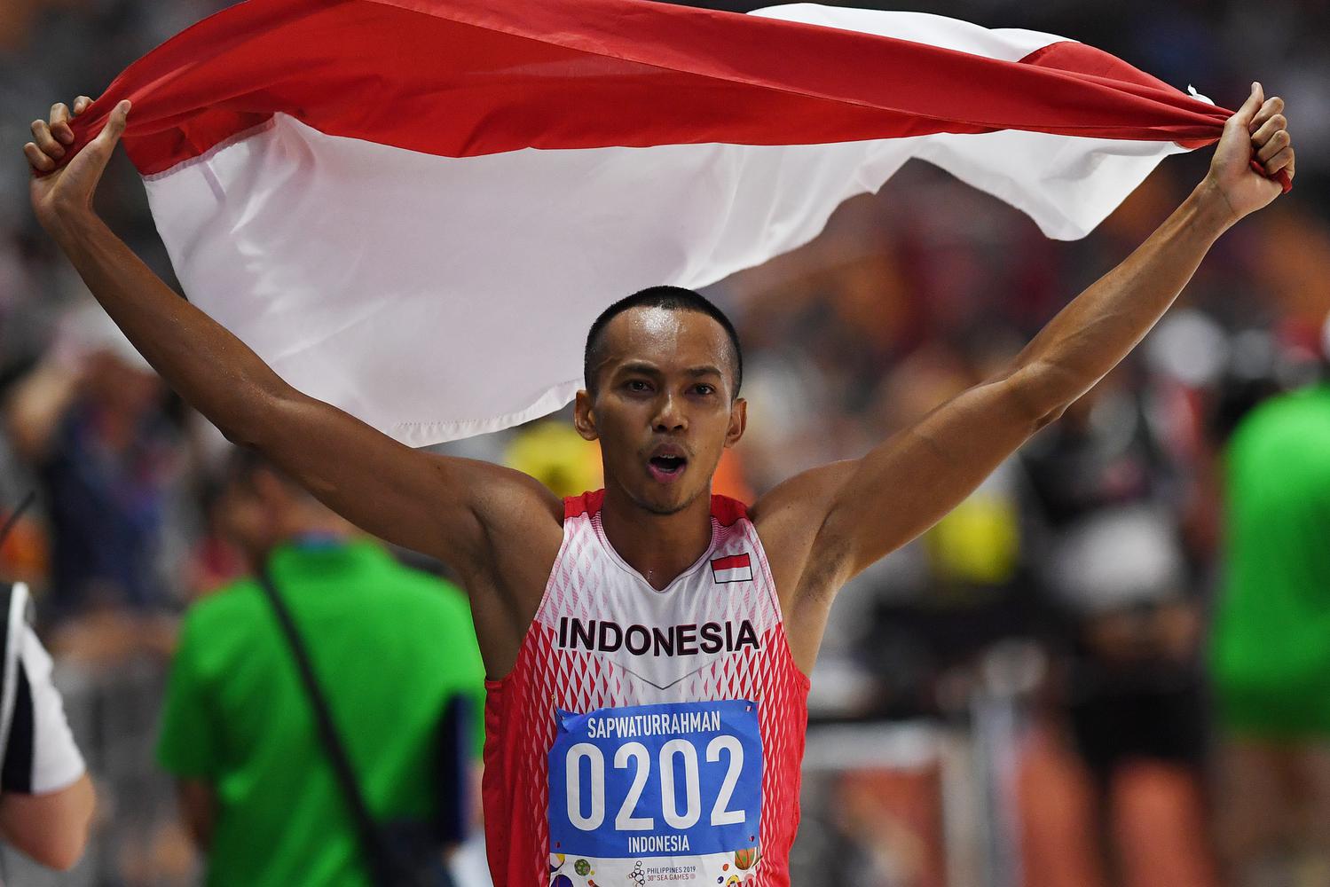 Atlet lompat jauh Indonesia Sapwaturrahman mengibarkan Bendera Merah Putih setelah berhasil memenangkan pertandingan Lompat Jauh Putra SEA Games ke-30 di Stadion Atletik New Clark, Filipina, Sabtu (7/12/2019). Sapwaturrahman berhasil meraih medali emas.