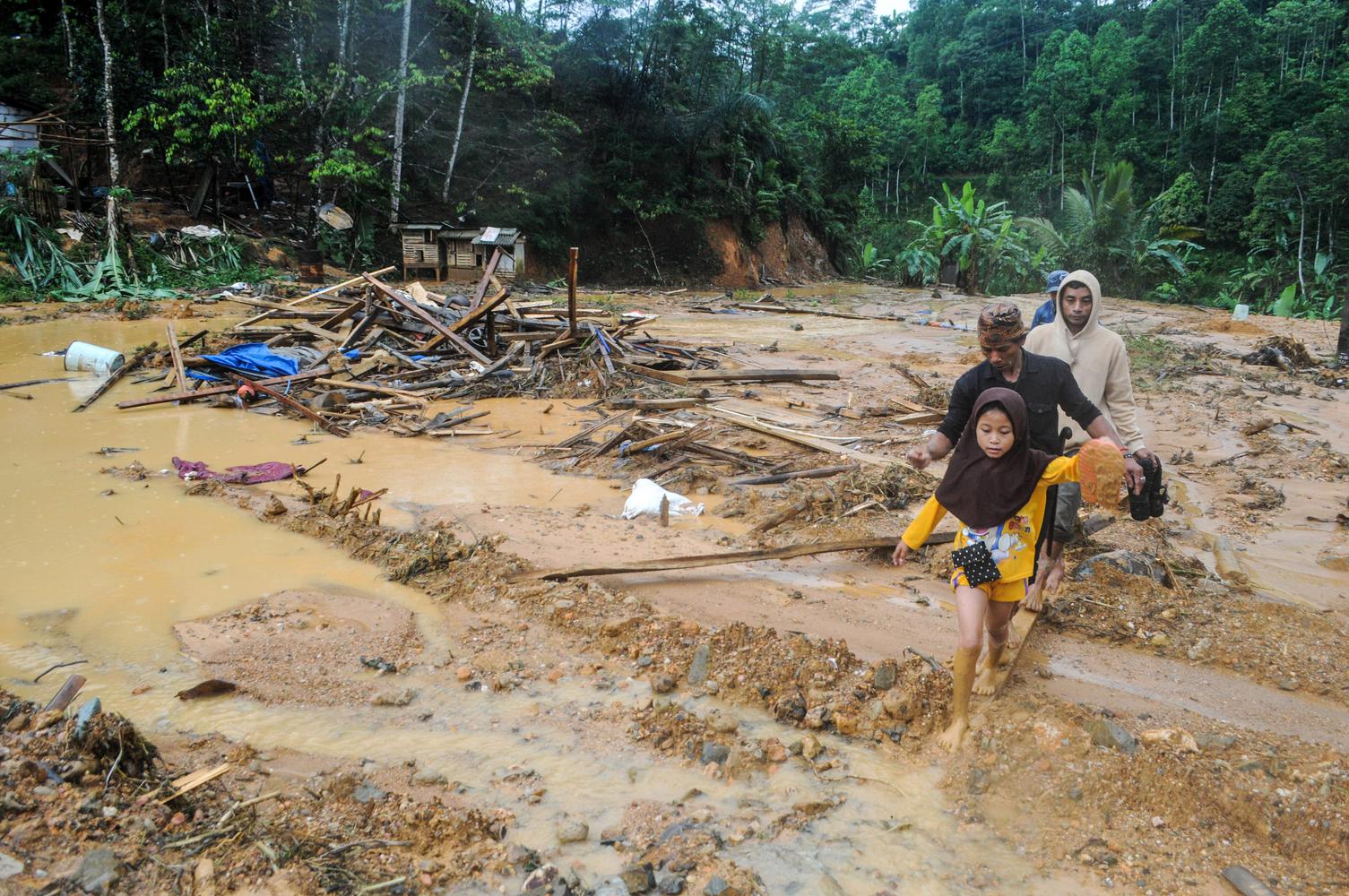 Sejumlah warga melintasi pemukiman yang rusak terdampak banjir bandang di Kampung Panggeleseran, Desa Citorek Kidul, Lebak, Banten, Minggu (8/12/2019). Pihak BPBD Kabupaten Lebak mencatat akibat hujan deras yang turun sejak Jumat (6/12) malam sebanyak 12 titik jalan kabupaten menuju Citorek tertutup material longsor, 3 jembatan antar desa terputus, dan 197 rumah rusak terendam banjir di 6 Desa dari 2 Kecamatan yaitu Cibeber dan Citorek.