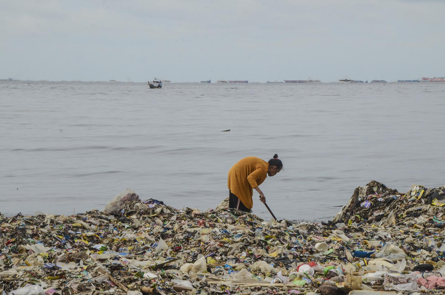 Warga beraktivitas di sekitar tumpukan sampah Pesisir laut Cilincing, Jakarta Utara, Selasa (10/12/2019). Sampah plastik yang menumpuk di sekitar pesisir laut Cilincing membahayakan kehidupan Biota Laut dan warga sekitar.