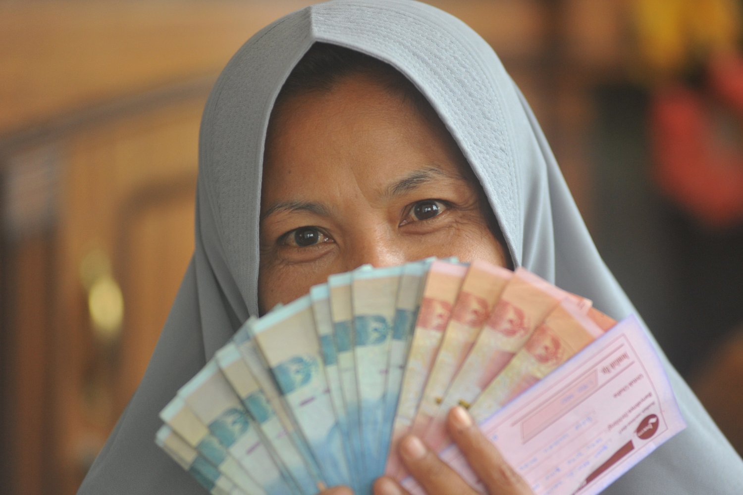Seorang nasabah tergabung dalam Kelompok Usaha Masyarakat Sekitar Pesantren Indonesia (Kumpi) memperlihatkan sejumlah uang yang dipinjamnya dari Bank Wakaf Mikro (BMW). mereka mendapatkan pinjaman modal usaha untuk menunjang ekonomi rumah tangga secara berkelompok dengan minimal anggota 15 orang dan maksimal 25 orang per kelompok.
