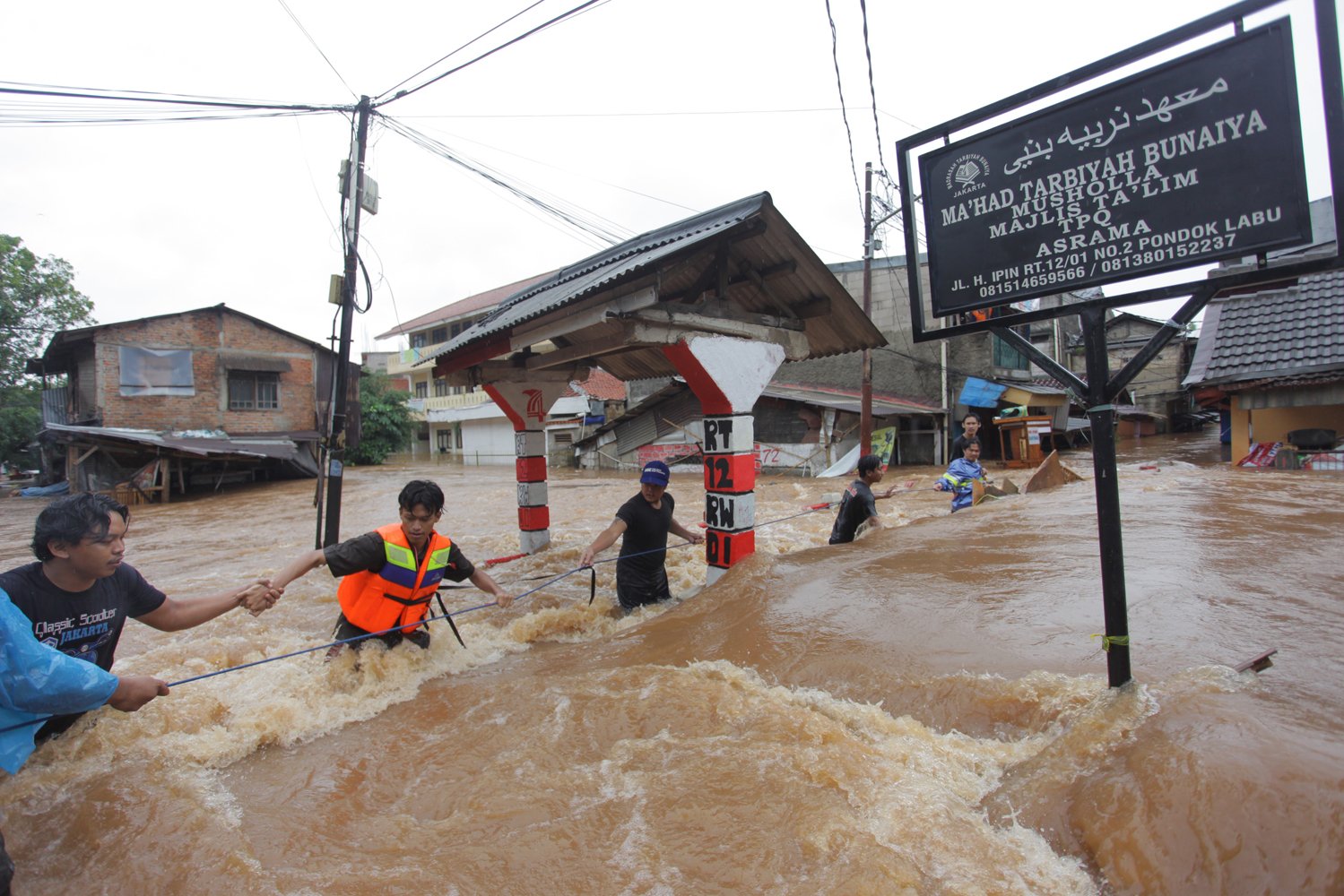 Warga melintasi banjir yang menggenangi Perumahan kawasan Jalan H. Ipin, Pondok Labu, Jakarta, Rabu (1/1/2020). Tingginya intensitas hujan sejak kemarin hingga pagi ini membuat jalan H.Ipin ke Pondok Labu ter putus. 
