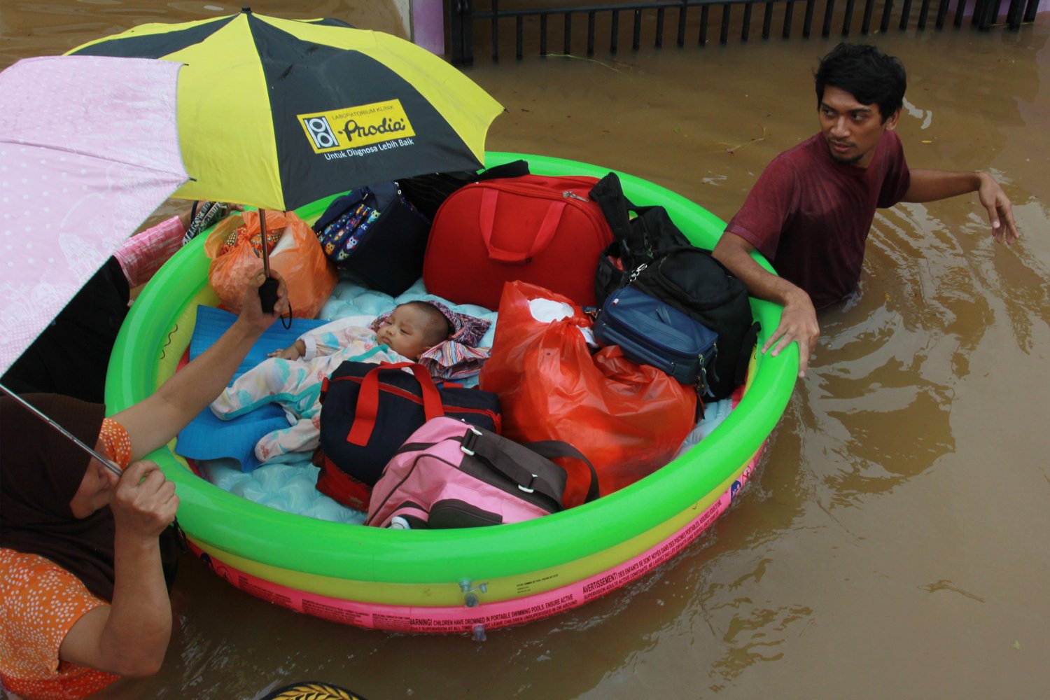 Warga dengan menggunakan perahu karet seadanya menyelamatkan bayinya dari dalam rumahnya yang terendam banjir di Perumaha Puri Bintaro Indah, Ciputat, Tangerang Selatan, Banten, Rabu (1/1/2020). Banjir yang menggenang setinggi 1,5 meter di perumahan tersebut akibat hujan deras seharian yang mengguyur kawasan tersebut serta meluapnya kali di sekitar perumahan itu. 
