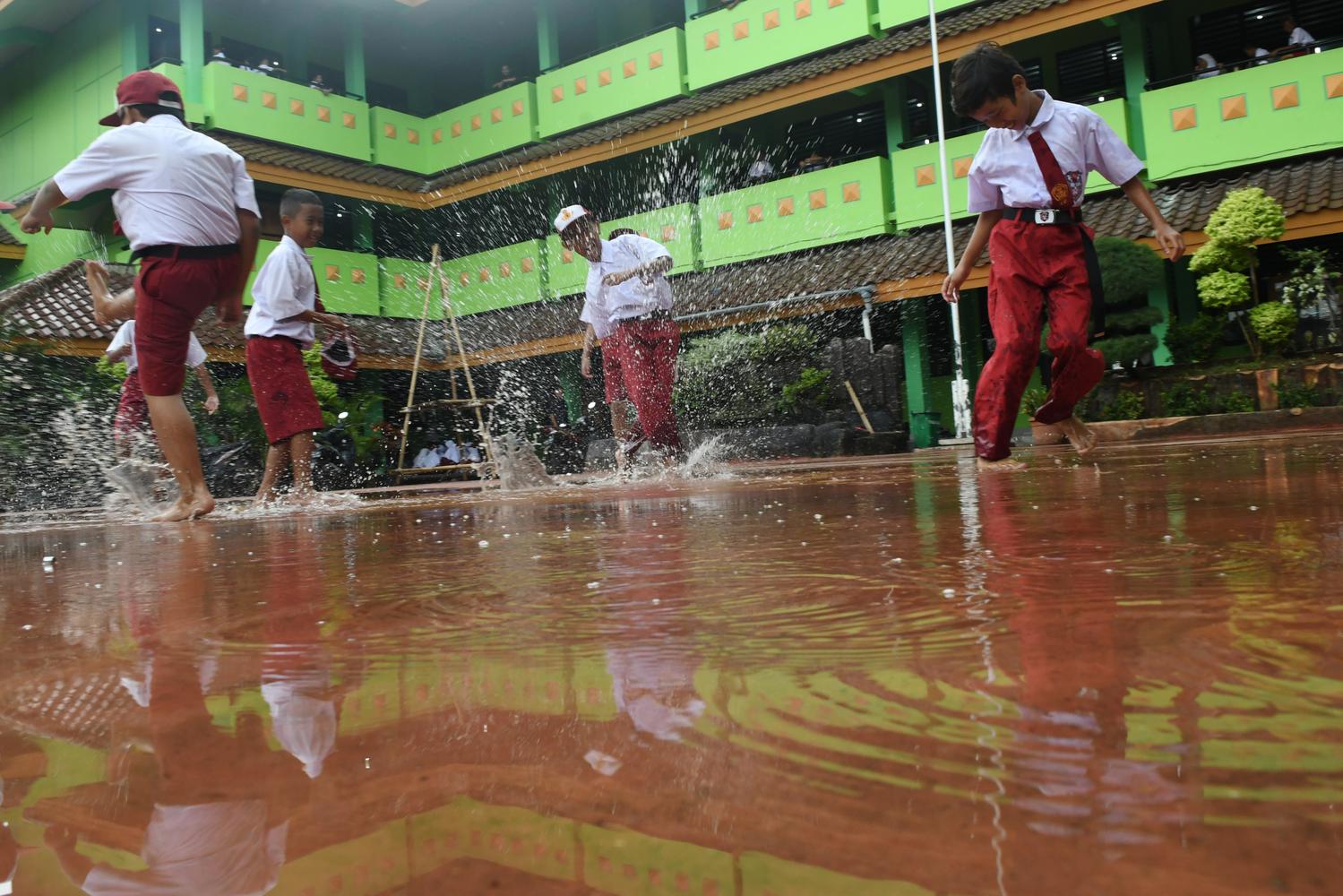 Siswa Sekolah Dasar Negeri Kapuk Muara 01 bermain air saat kerja bakti bersama pasca banjir di Jakarta, Senin (6/1/2019). Kegiatan belajar mengajar di sejumlah sekolah terdampak banjir belum efektif karena selain ruangan kelas terendam air juga digunakan sebagai tempat pengungsian.
