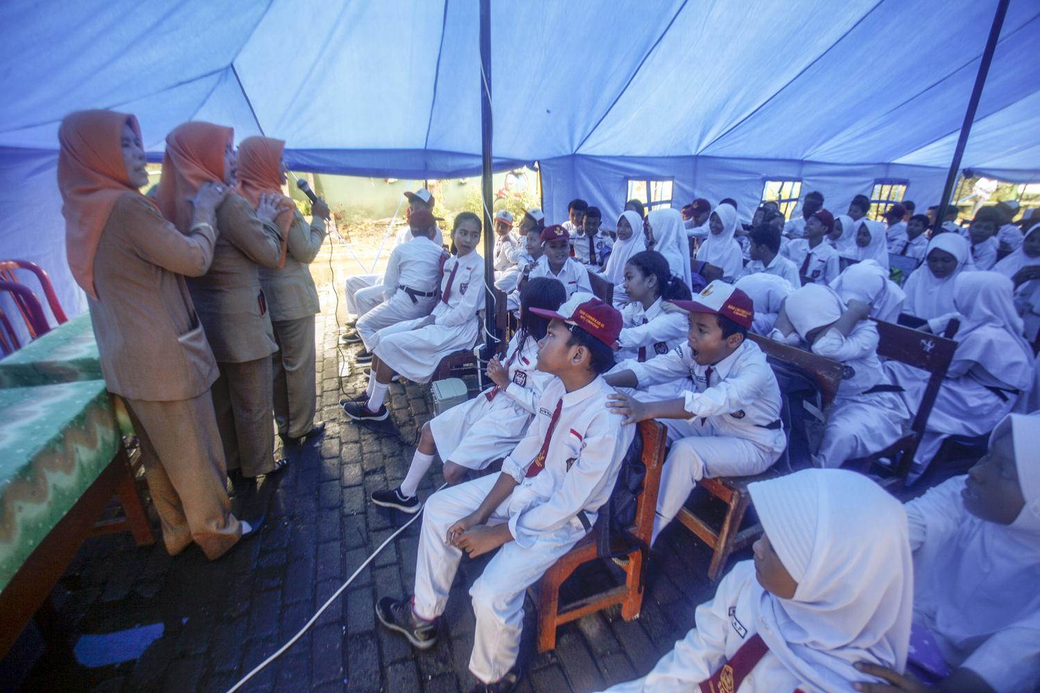 Sejumlah siswa gabungan beberapa kelas SDN Cirimekar 02 belajar di tenda darurat di Cibinong, Kabupaten Bogor, Jawa Barat, Senin (6/1/2020). Akibat atap ruang kelas ambruk membuat siswa belajar di tenda darurat pada hari pertama sekolah pasca libur panjang.