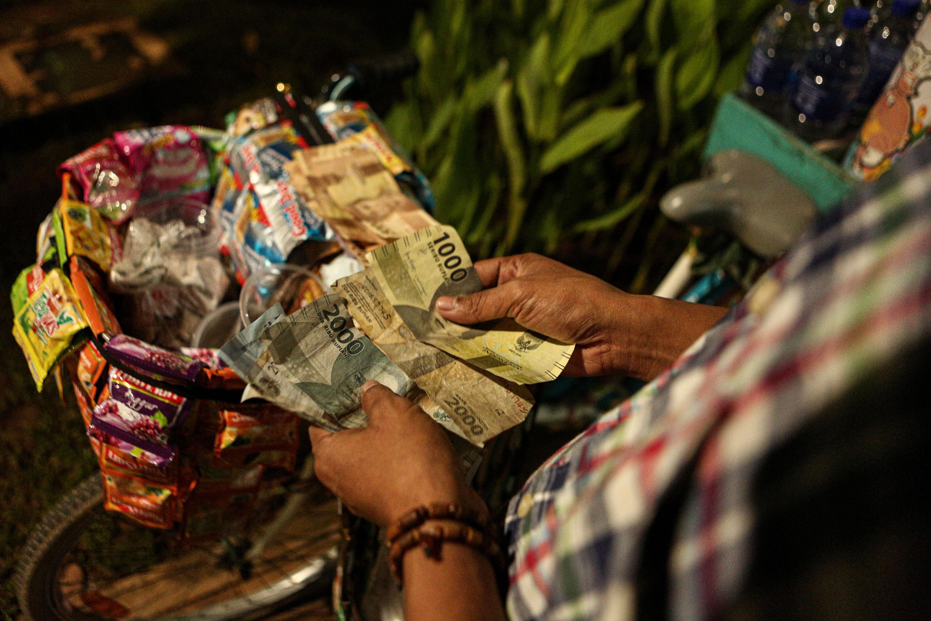 Hendra (30) menghitung uang hasil berjualan kopi keliling di Kawasan Taman Menteng, Jakarta Pusat.