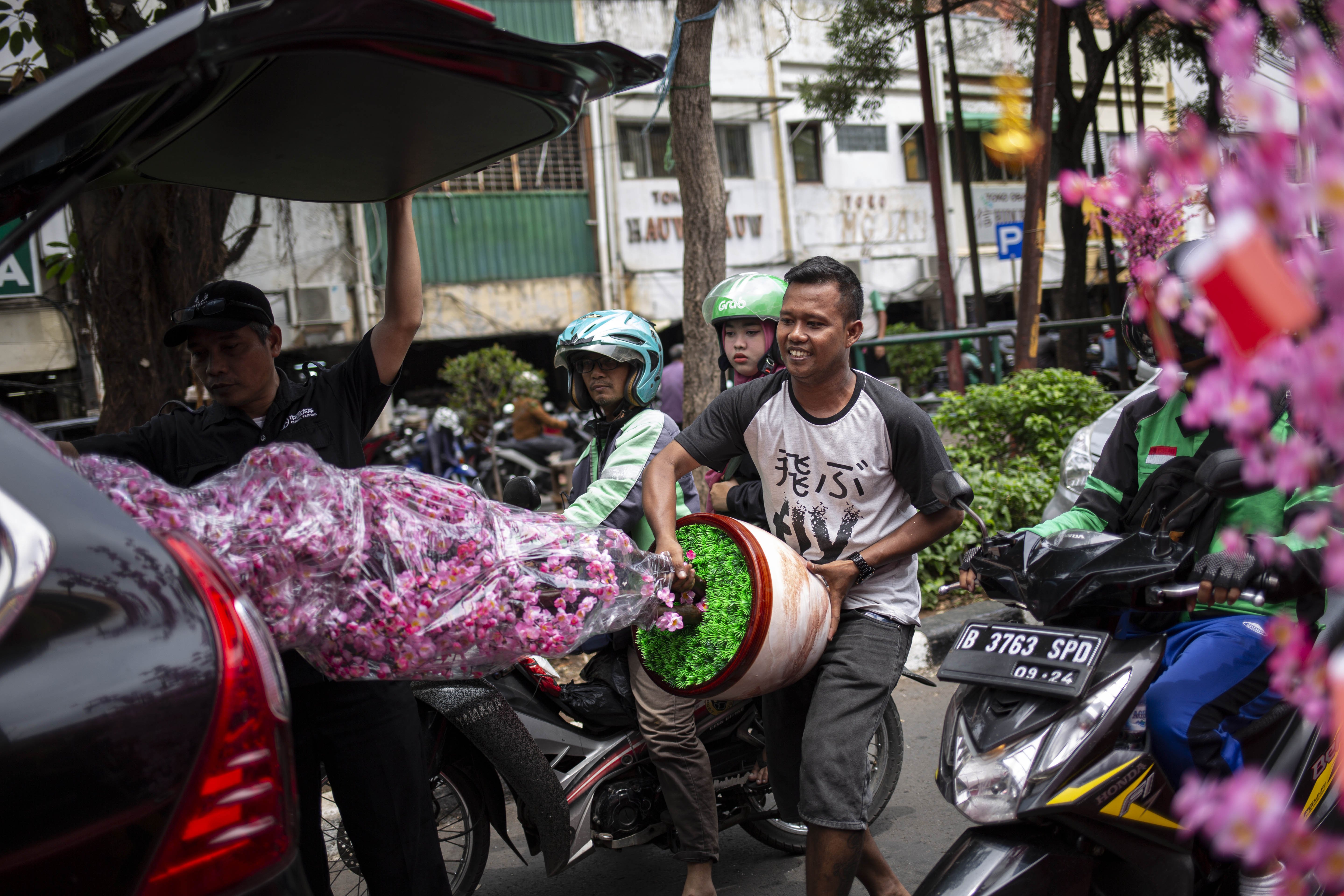 Pedagang memindahkan pohon hiasan imlek ke dalam mobil yang dibeli di Pasar Petak Sembilan, Pancoran, Glodok, Jakarta Barat, Selasa (21/1/2020). 