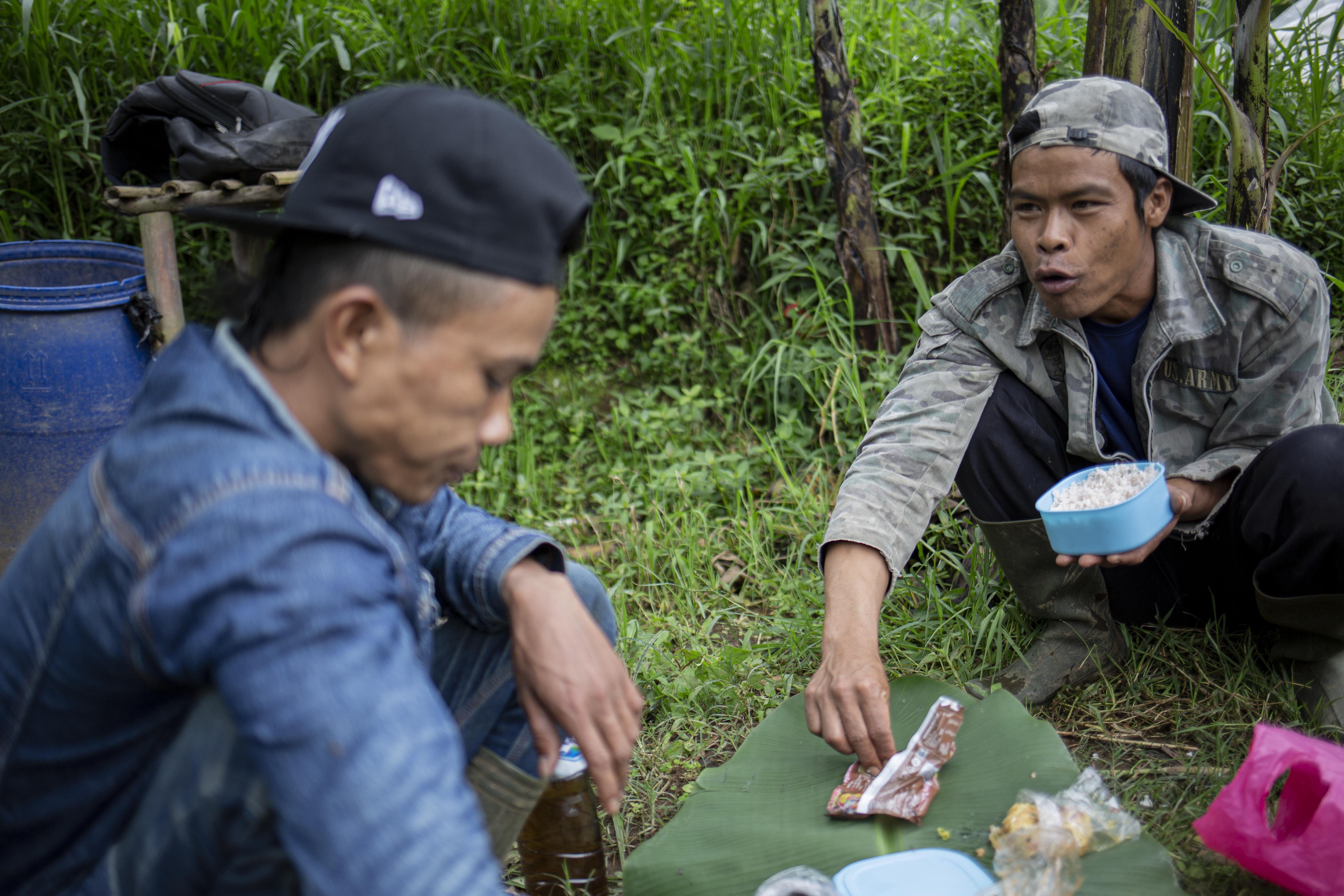 Ubet dan Yayat menyantap makanan yang dibawa dari rumah di tengah perjalanan berburu madu hutan di Tengah Hutan Palalngon, Minggu (1/3/2020).