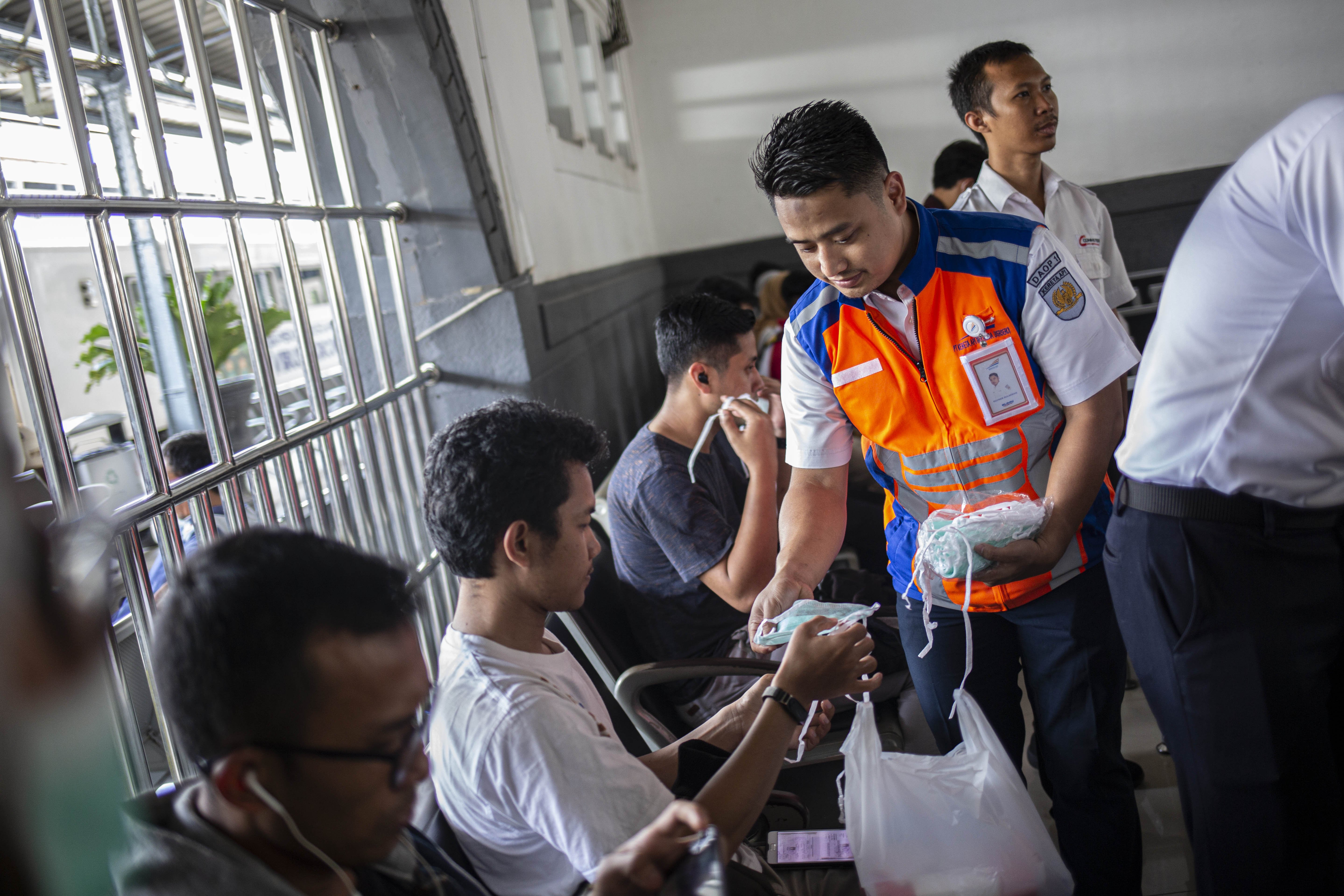 Petugas KAI memberikan masker kepada penumpang di Stasiun Pasar Senen, Jakarta Pusat, Senin (9/3/2020). PT. KAI melakukan sosialisasi pencegahan virus corona serta pembagian masker dan hand sanitazer kepada penumpang guna mencegah penyebaran virus corona.