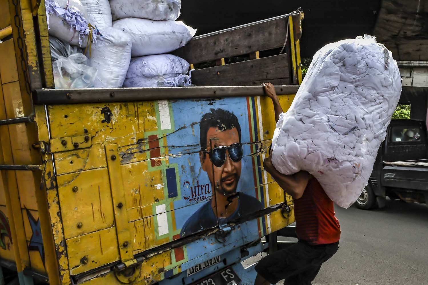 Pekerja memasukan limbah sisa kain ke dalam truk di Jakarta. 