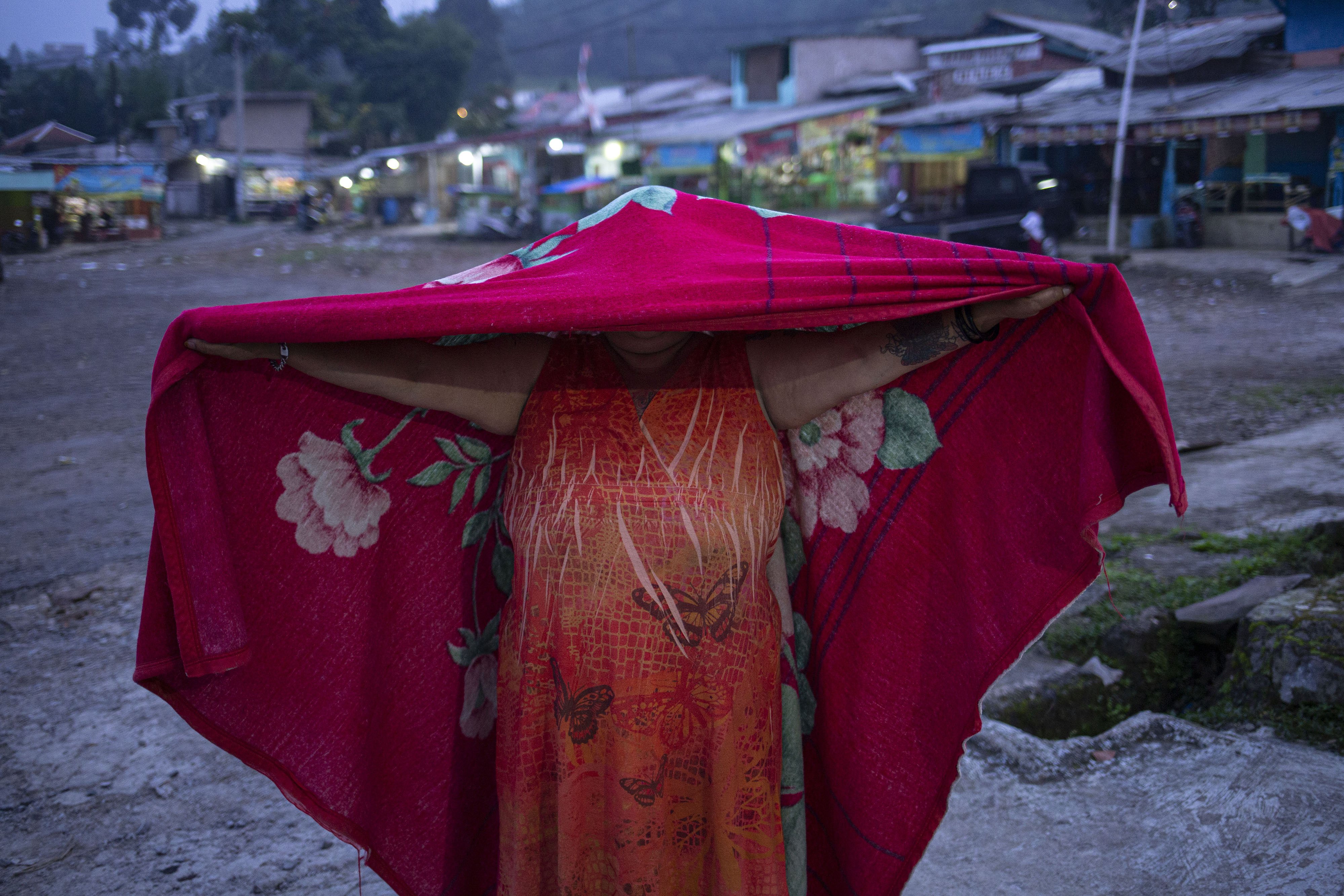 Neti Herawati alias Bude Sumiyati menutupi wajahnya dengan selimut kesukaannya.