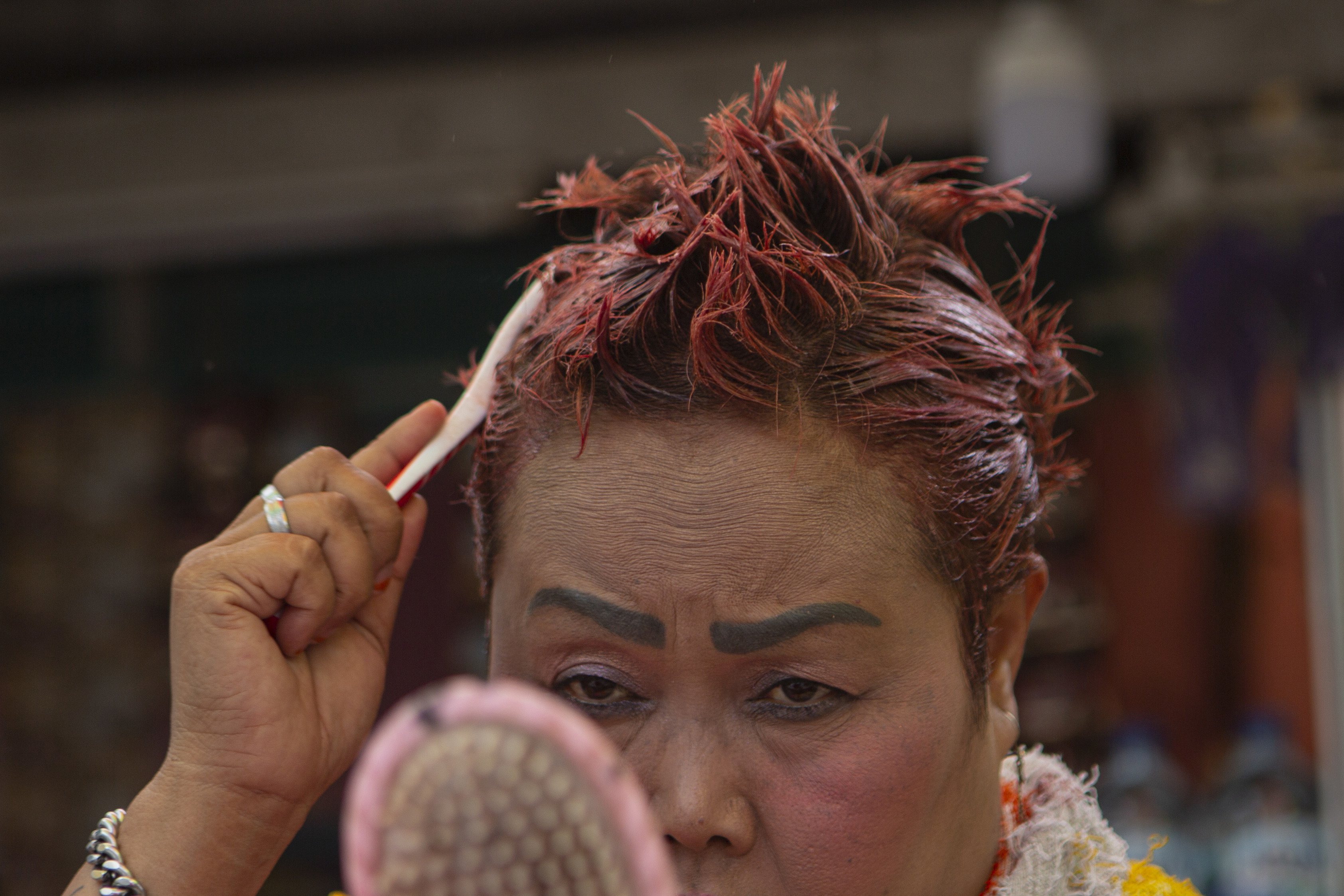 Bude Sumiyati tampak serius mengecat rambutnya dengan warna pink.