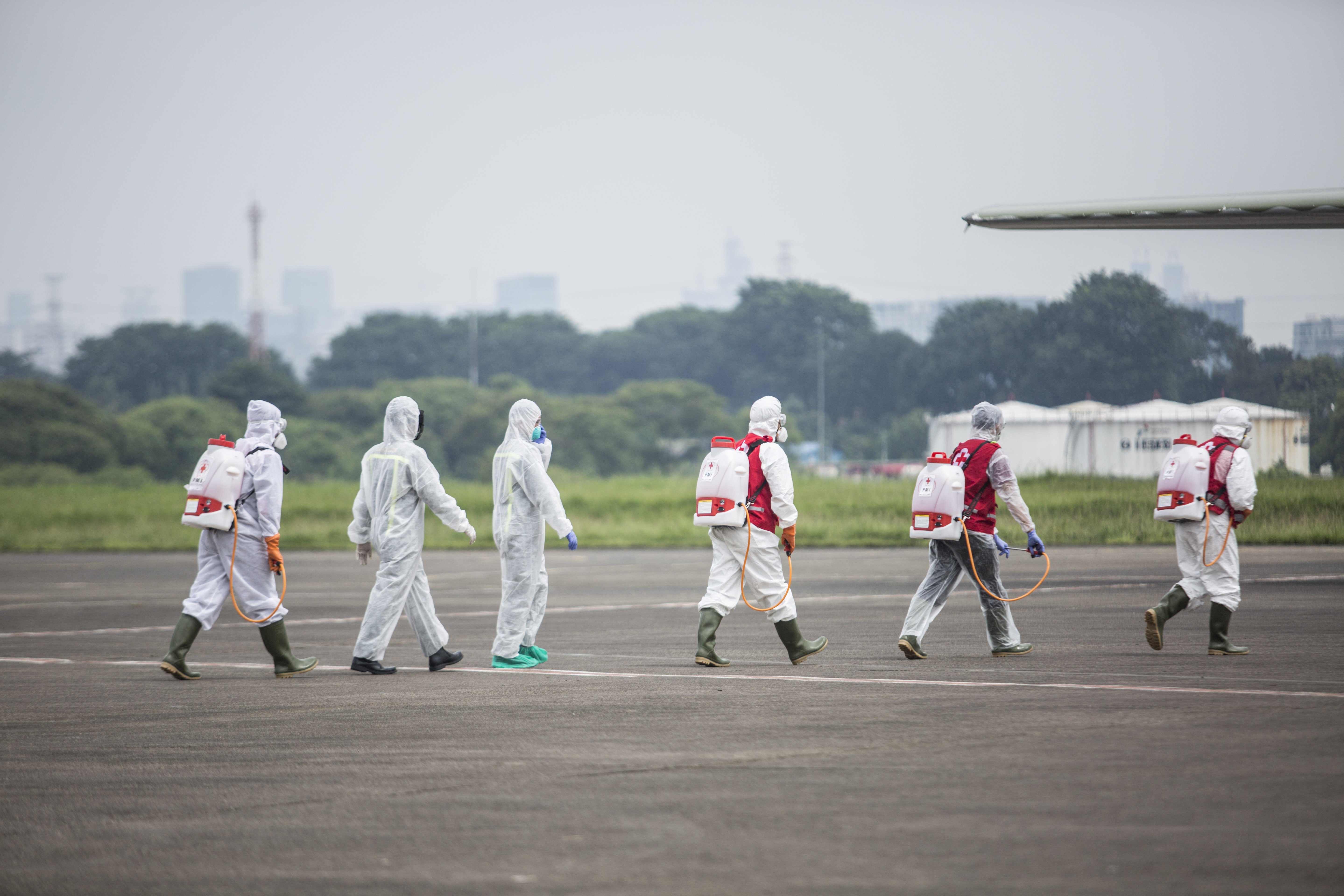 Petugas Palang Merah Indonesia (PMI) bersiap menyemprotkan disinfektan kepada kru dan pesawat Hercules C-130 TNI AU di Lanud Halim PerdanaKusumah, Jakarta Timur, Senin (23/3/2020).