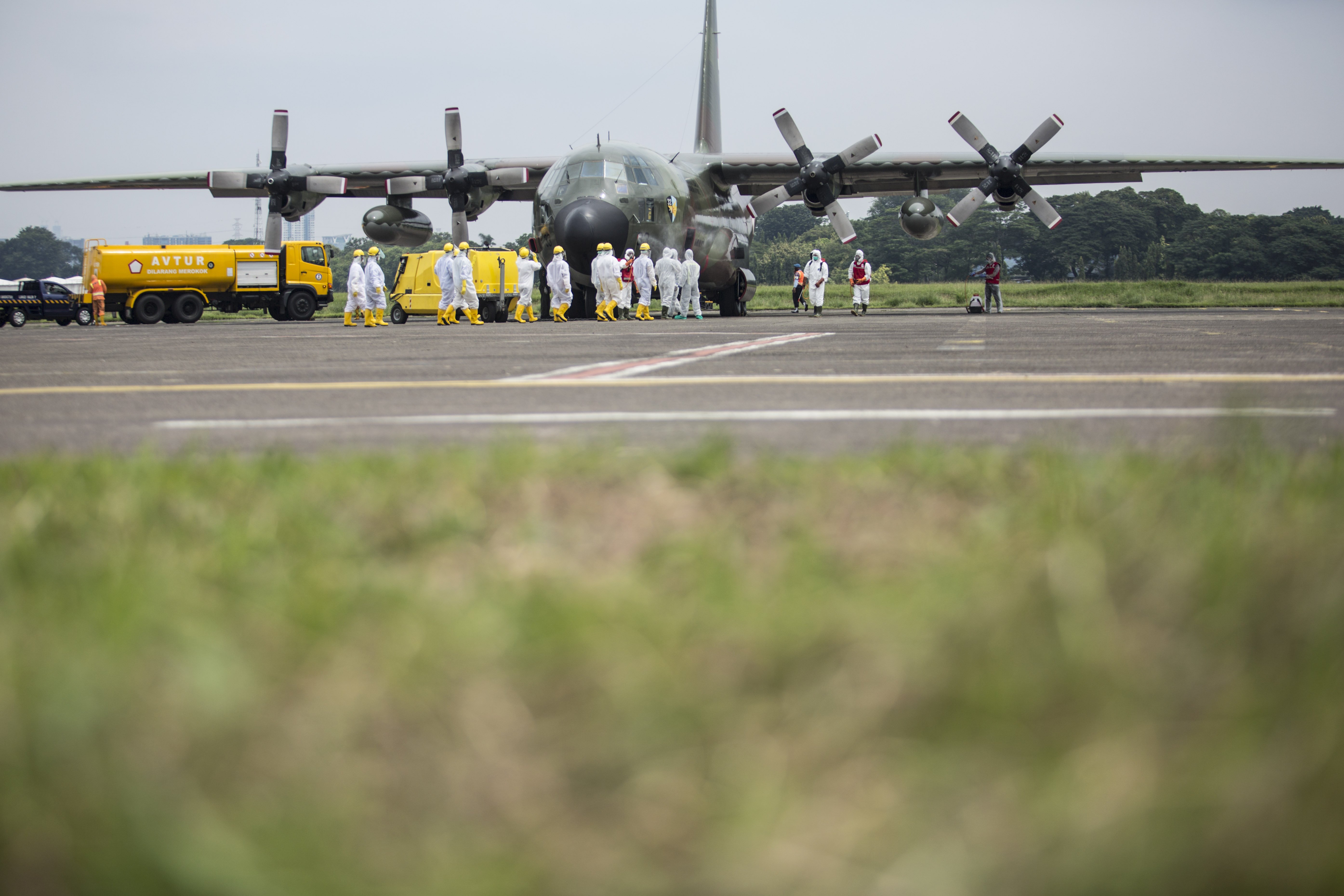 Petugas PMI menyemprotkan cairan disinfektan pada pesawat C-130 Hercules TNI AU dari Skadron Udara 32 Wing Udara 2 Lanud Abdulrachman Saleh Malang yang membawa alat kesehatan untuk penanganan COVID-19 setibanya di Lanud Halim Perdanakusuma, Jakarta, Senin (23/3/2020).