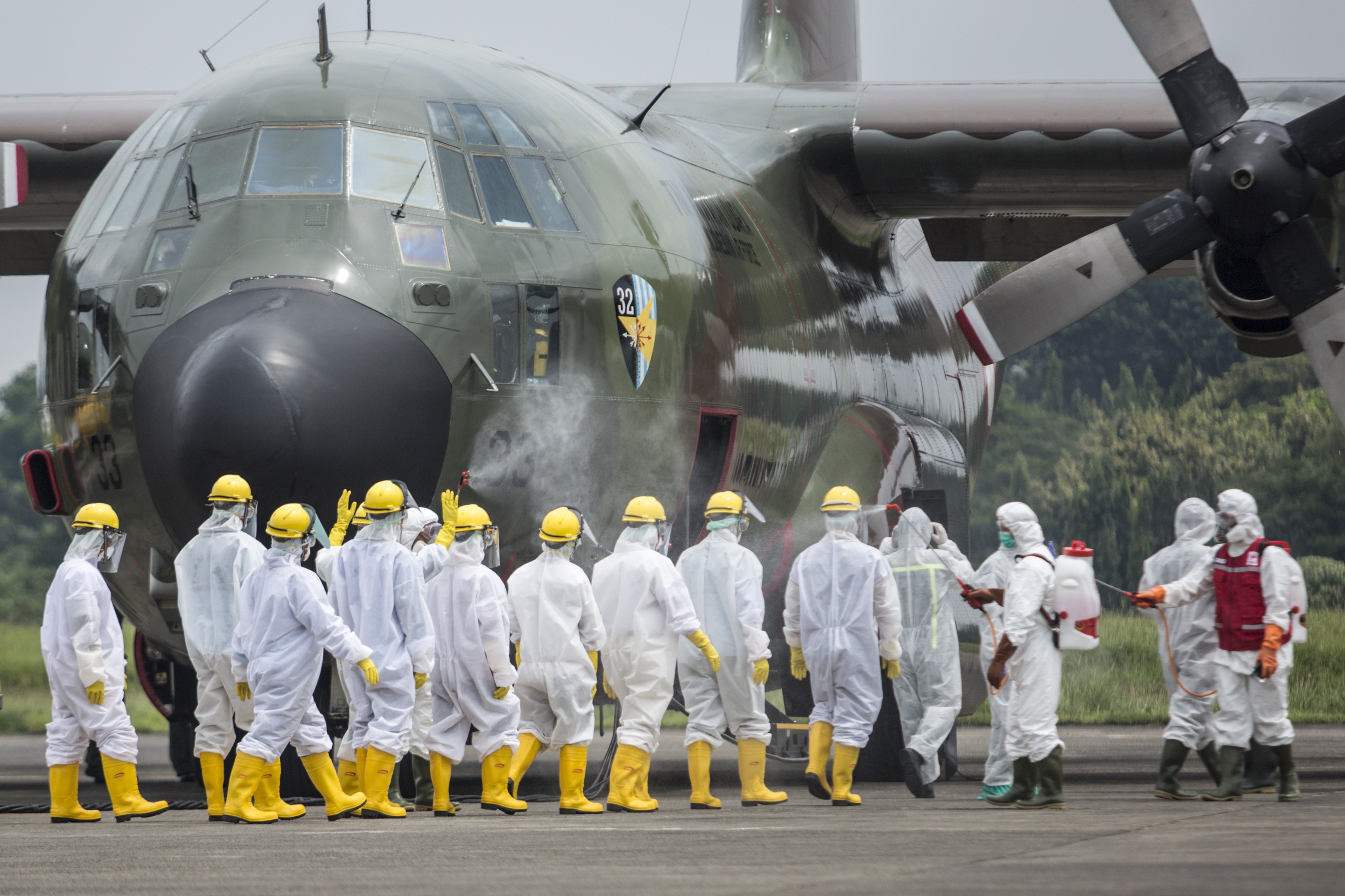 Petugas Palang Merah Indonesia (PMI) menyemprotkan cairan disinfektan kepada kru pengangkut setibanya pesawat Hercules A-130 pembawa alat kesehatan dari Shanghai, China tiba di Lanud Halim Perdanakusumah, Jakarta Timur, Senin (23/3/2020).