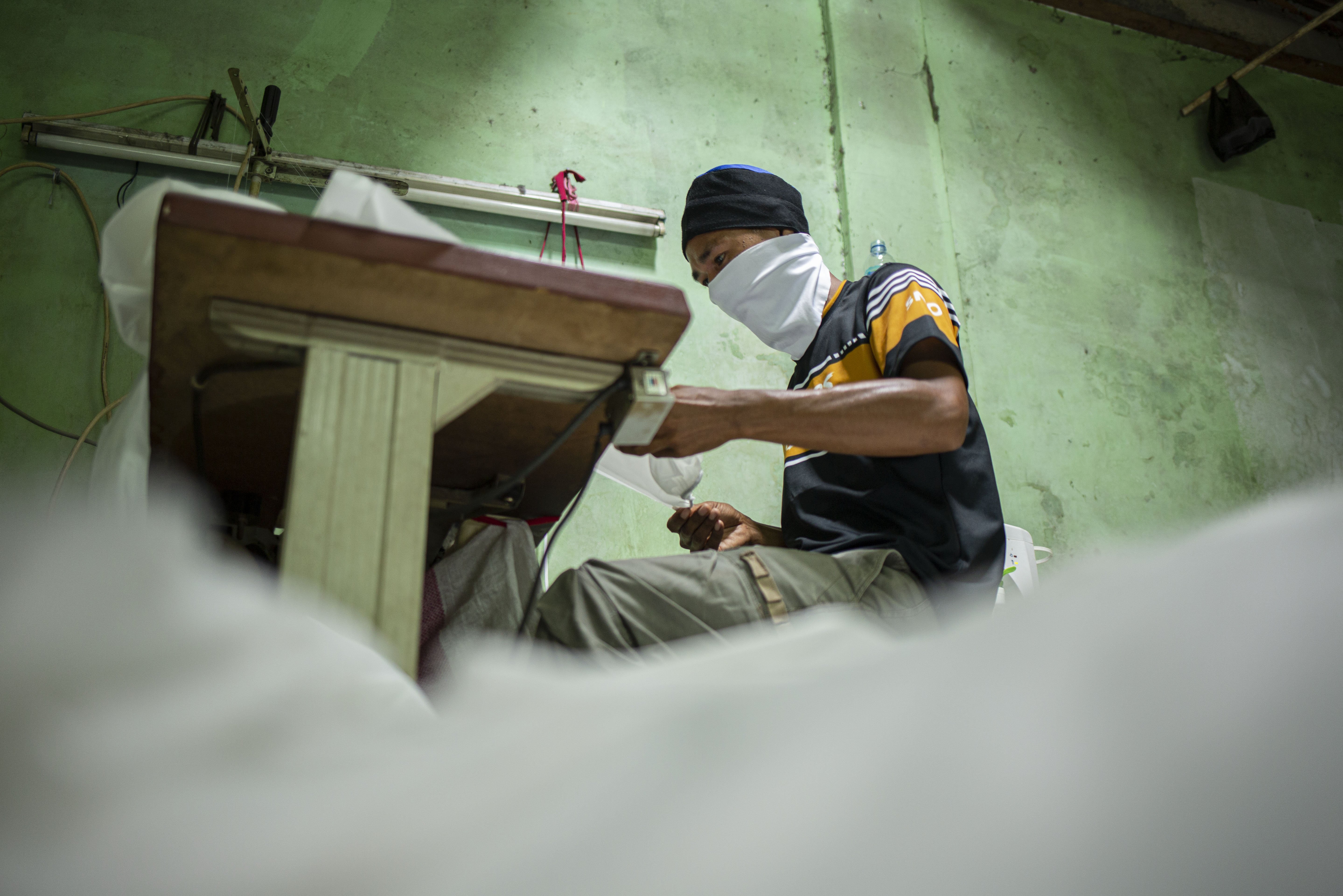 Pekerja menggunakan pakaian Alat Pelindung Diri (APD) tenaga medis di Pusat Industri Kecil, Penggilingan, Jakarta Timur, Rabu (24/3). Lonjakan jumlah kasus penyebaran virus corona (COVID-19) di beberapa wilayah menyebabkan terbatasnya ketersediaan alat perlindungan diri (APD). Pakaian untuk alat perlindungan diri tersebut dijual dengan harga Rp. 100.000.