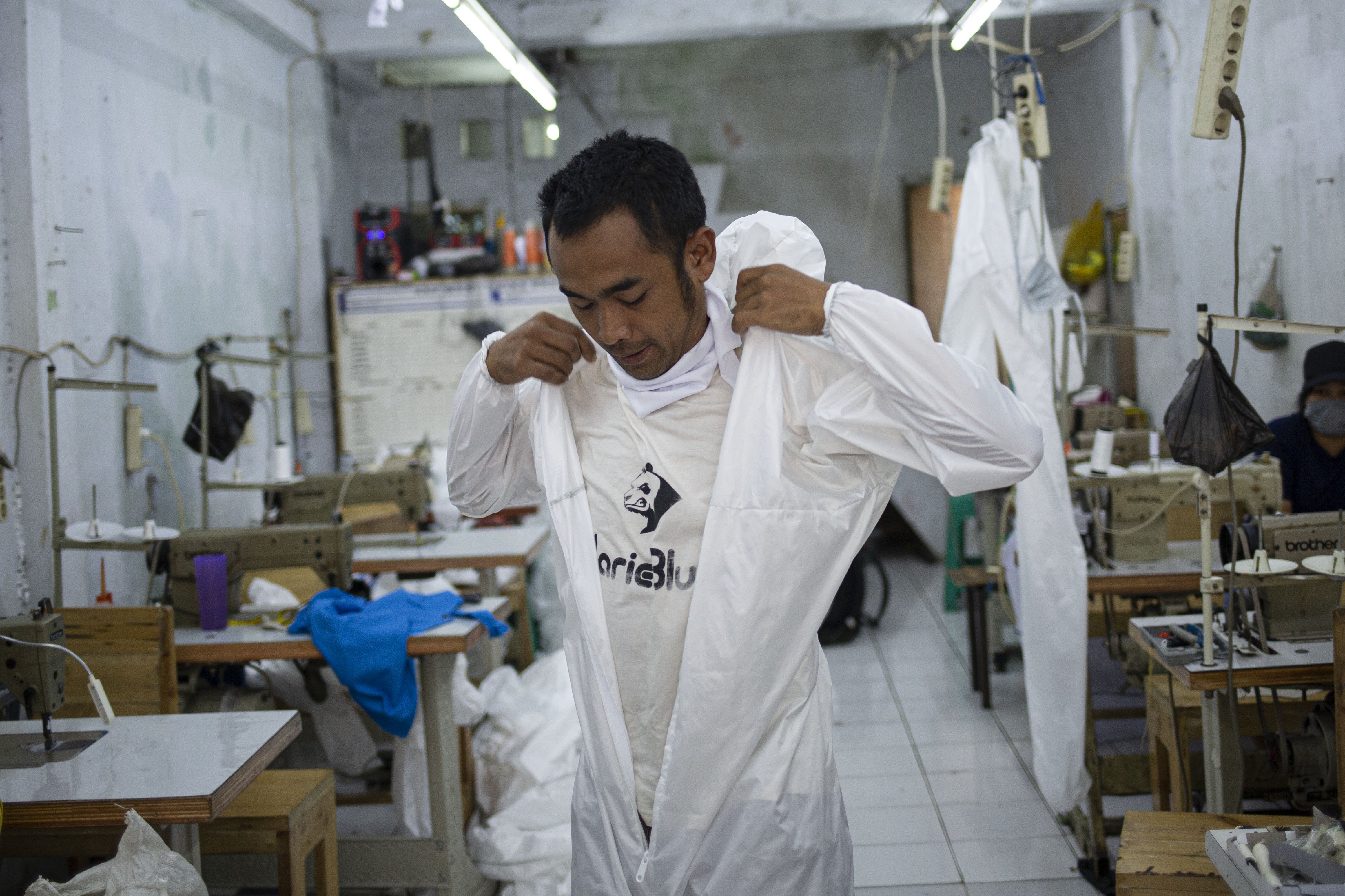 Pekerja menggunakan pakaian Alat Pelindung Diri (APD) tenaga medis di Pusat Industri Kecil, Penggilingan, Jakarta Timur, Rabu (24/3). Lonjakan jumlah kasus penyebaran virus corona (COVID-19) di beberapa wilayah menyebabkan terbatasnya ketersediaan alat perlindungan diri (APD). Pakaian untuk alat perlindungan diri tersebut dijual dengan harga Rp. 100.000.