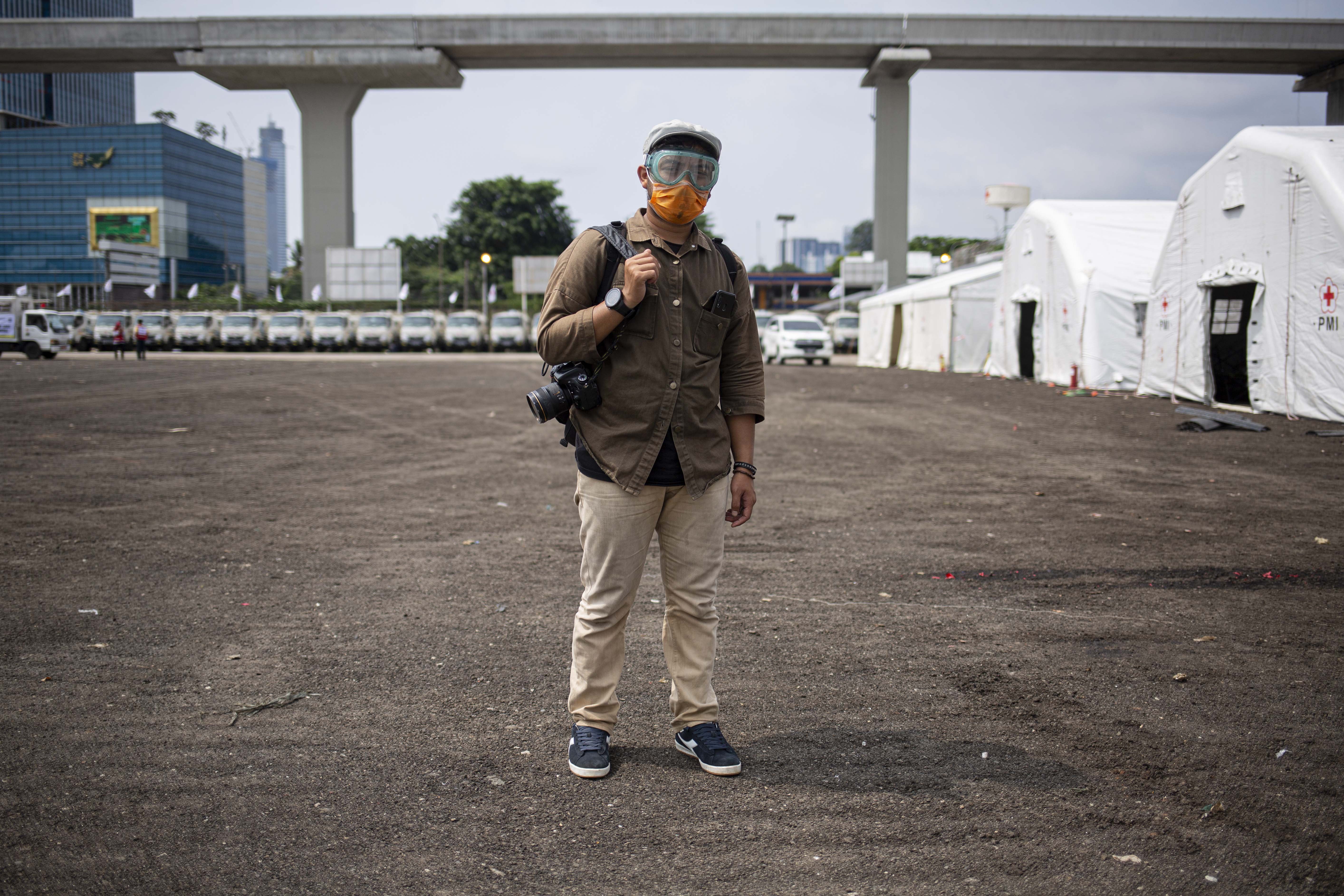 Thoudy Badai (25), pewarta foto di salah satu media nasional tetap bekerja meliput peristiwa di Jakarta dengan menggunakan masker dan kacamata salah satu antisipasi penyebaran virus Covid-19.