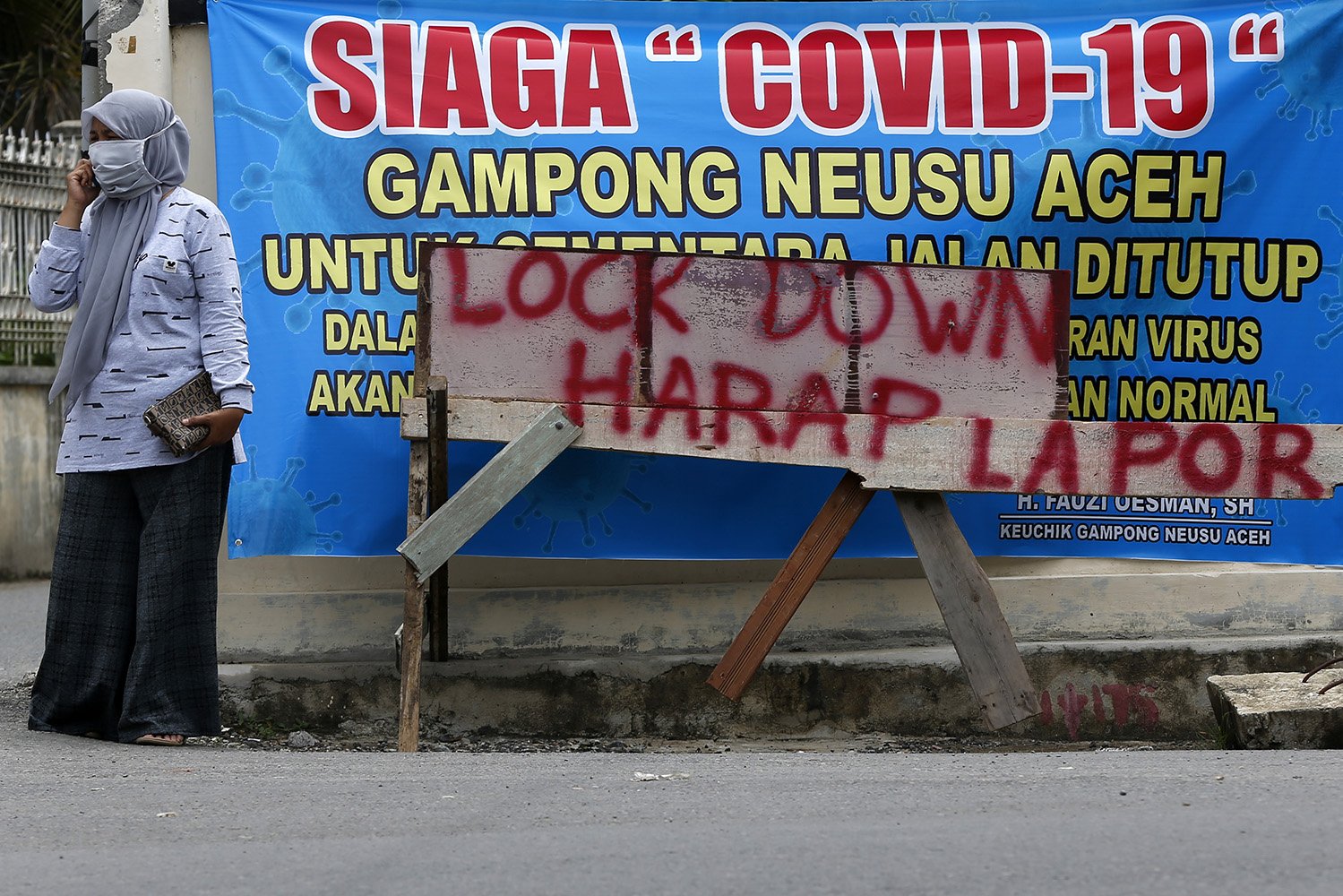 Warga berdiri di dekat pintu yang digunakan untuk karantina wilayah mandiri atau penutupan jalan akses masuk ke permukiman penduduk di Banda Aceh, Aceh. Aksi karantina wilayah mandiri Gampong (Desa) di Banda Aceh masih berlanjut sebagai upaya untuk mencegah penularan dan penyebaran virus Corona (COVID-19). 