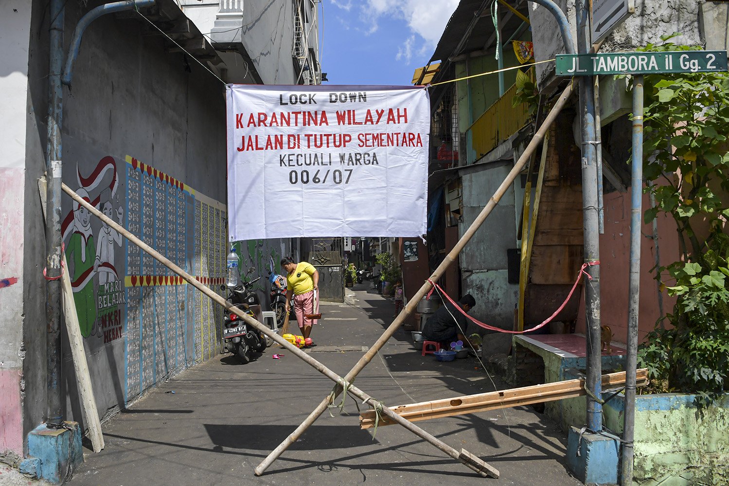 Warga menyampu jalan di kawasan Tambora, Jakarta. Warga setempat memberlakukan karantina wilayah secara mandiri dengan menutup beberapa akses jalan masuk perkampungan serta meningkatkan keamanan untuk mencegah penyebaran COVID-19. \r\n