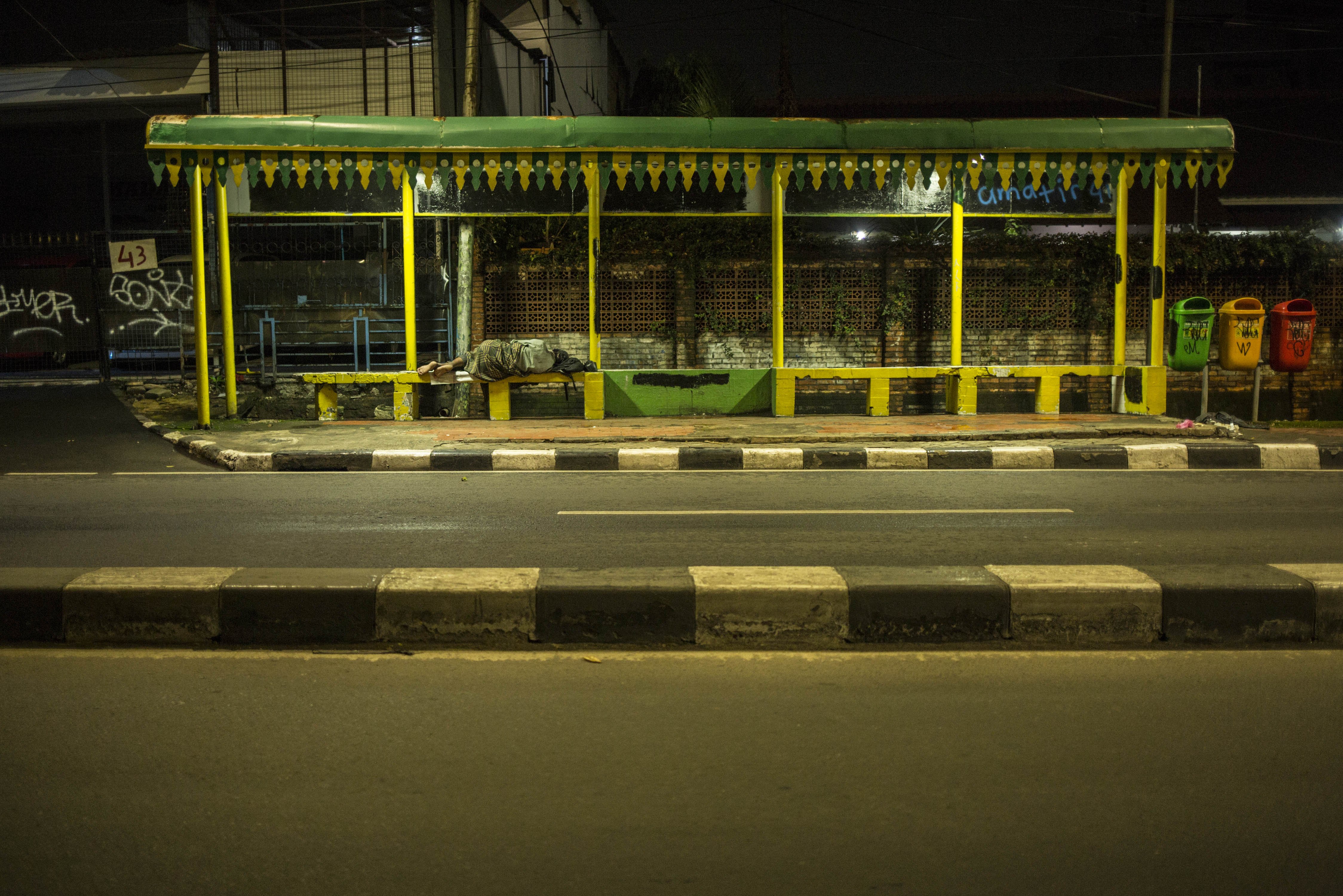 Tuna wisma tertidur di Halte Bus di Jalan Fatmawati, Jakarta Selatan, Selasa (14/4/2020). Pemberlakuan Pembatasan Sosial Bersekala Besar (PSBB) membuat jalan protokol Jakarta dan pusat keramaian tampak lenggang.