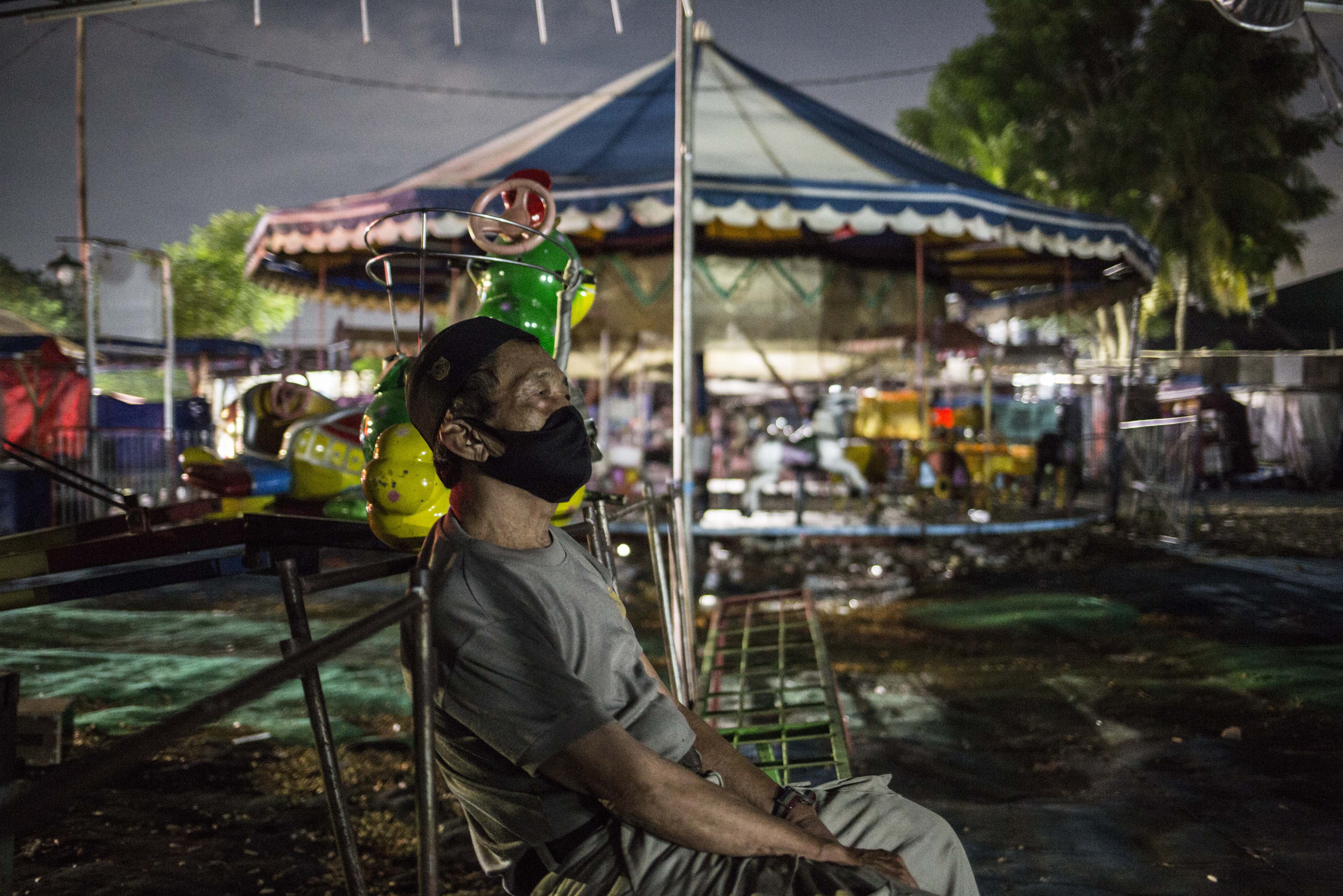 Pengelola Pasar Malam Duren Sawit, Jakarta Timur, Aji Mujiono (76) beristirahat di wahana permainan. Pasar malam tersebut terbengkalai sejak 20 Maret 2020 akibat merebaknya virus Covid-19 dan diberlakukannya Pembatasan Sosial Bersekala Besar (PSBB).