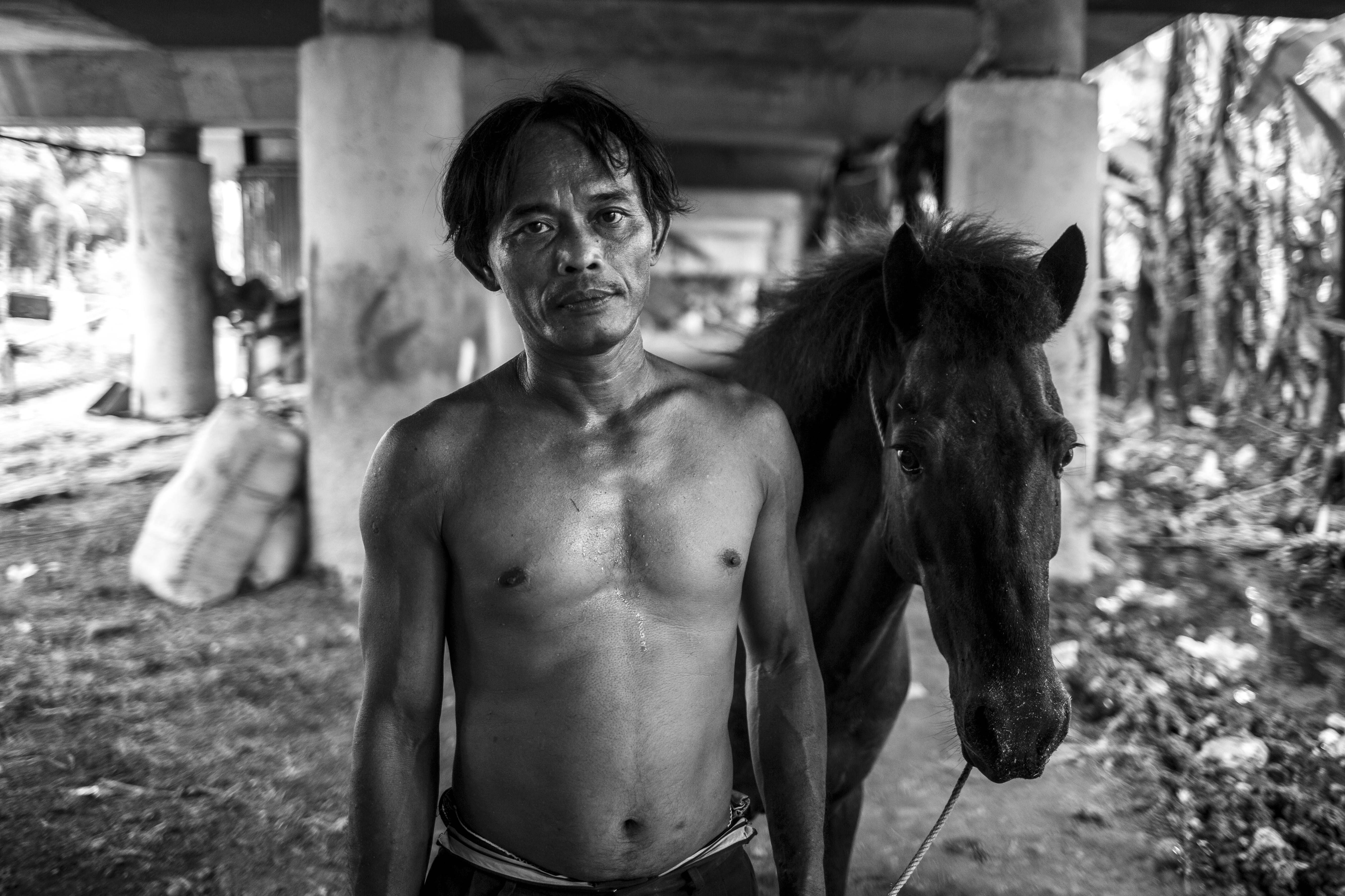 Hariyanto (45) berfoto bersama kudanya di bawah kolong tol Kawasan Sungai Bambu, Jakarta Utara, Selasa (12/5/2020).